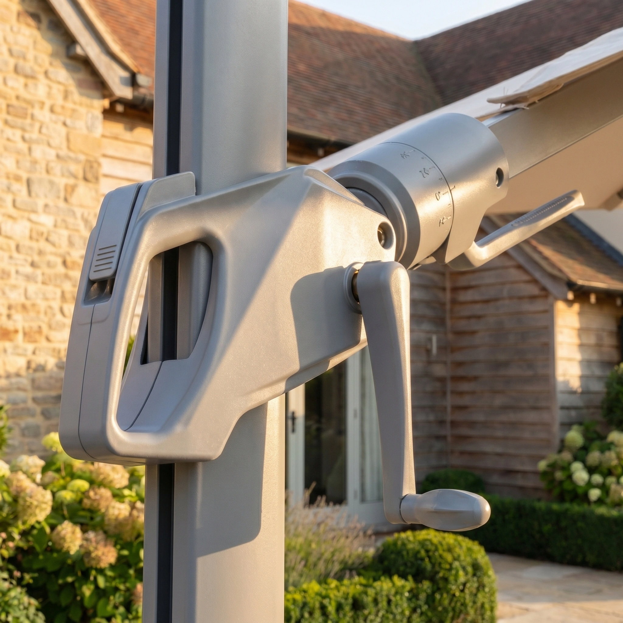 Close-up of the crank handle on the Hera 3m x 2m Rectangular Cantilever Parasol with LED Lighting in Beige, featuring a UV protection canopy, set against a house and garden backdrop.