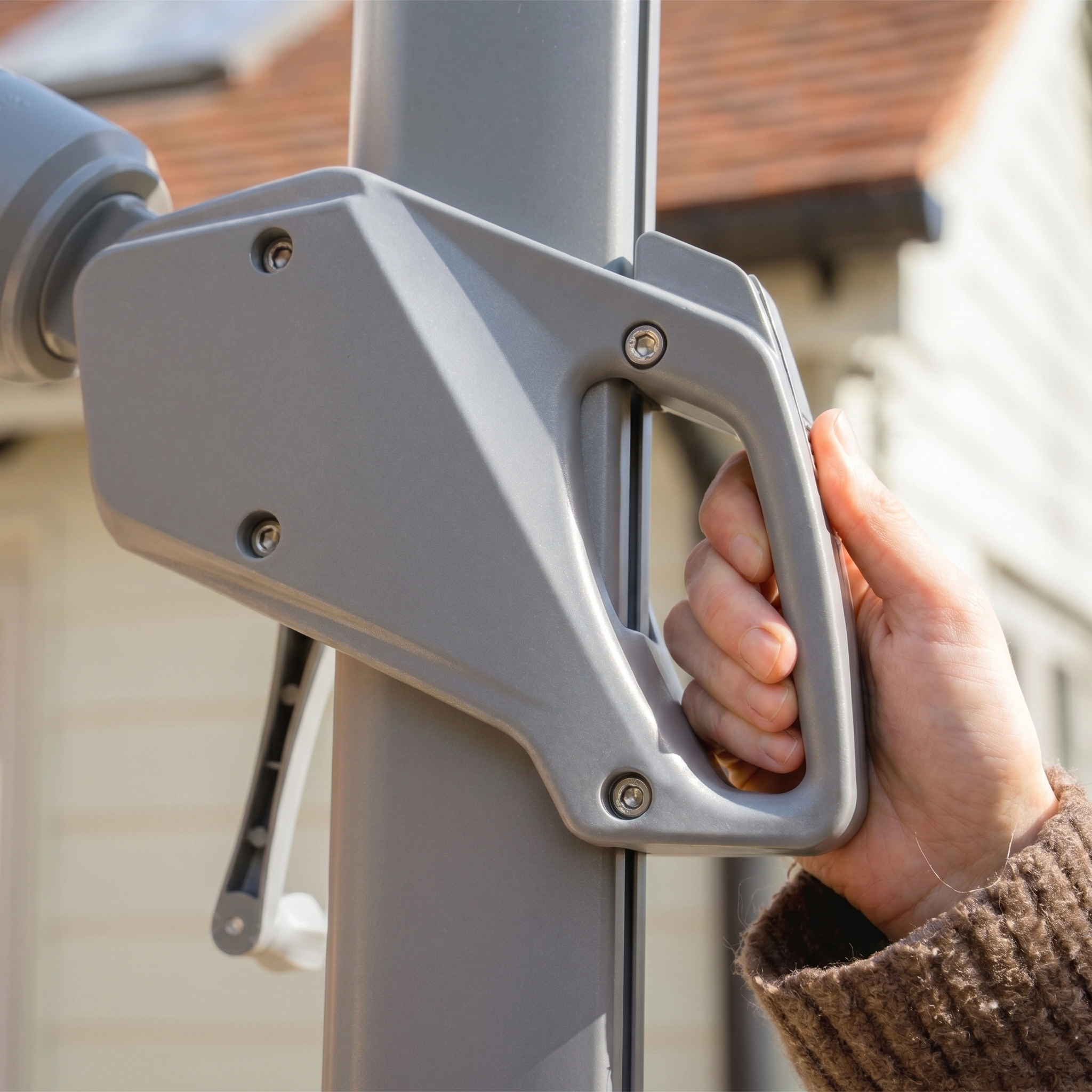 Close-up of a hand gripping the handle of the Hera 3m x 2m Rectangular Cantilever Parasol with LED Lighting in Charcoal, attached to its metal pole and positioned outdoors in sunlight.