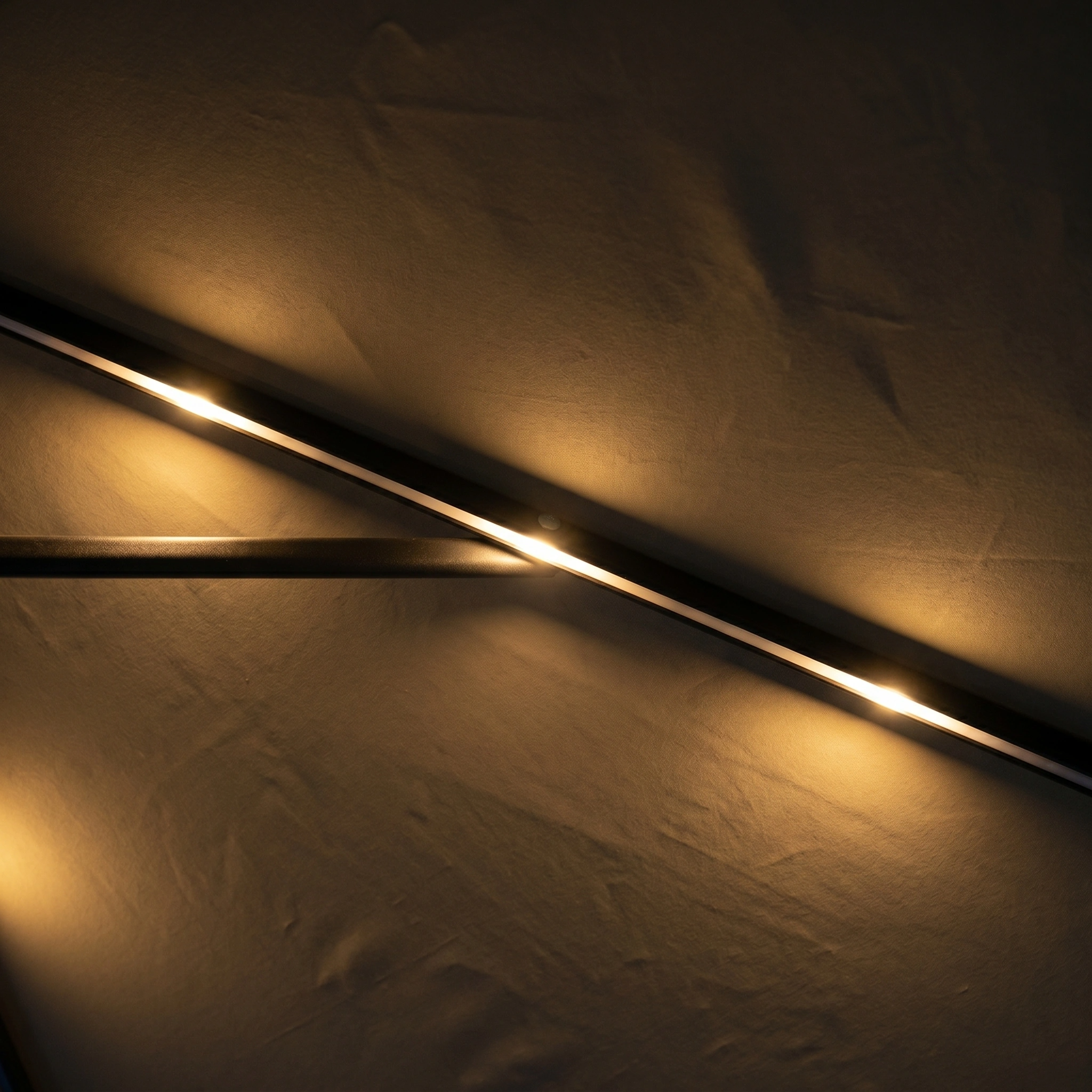 Diagonal LED light strips glow on a softly textured beige wall in a dark room, evoking the ambient glow of the Hera 3m Round Cantilever Parasol with LED Lighting in Beige on a calm evening.