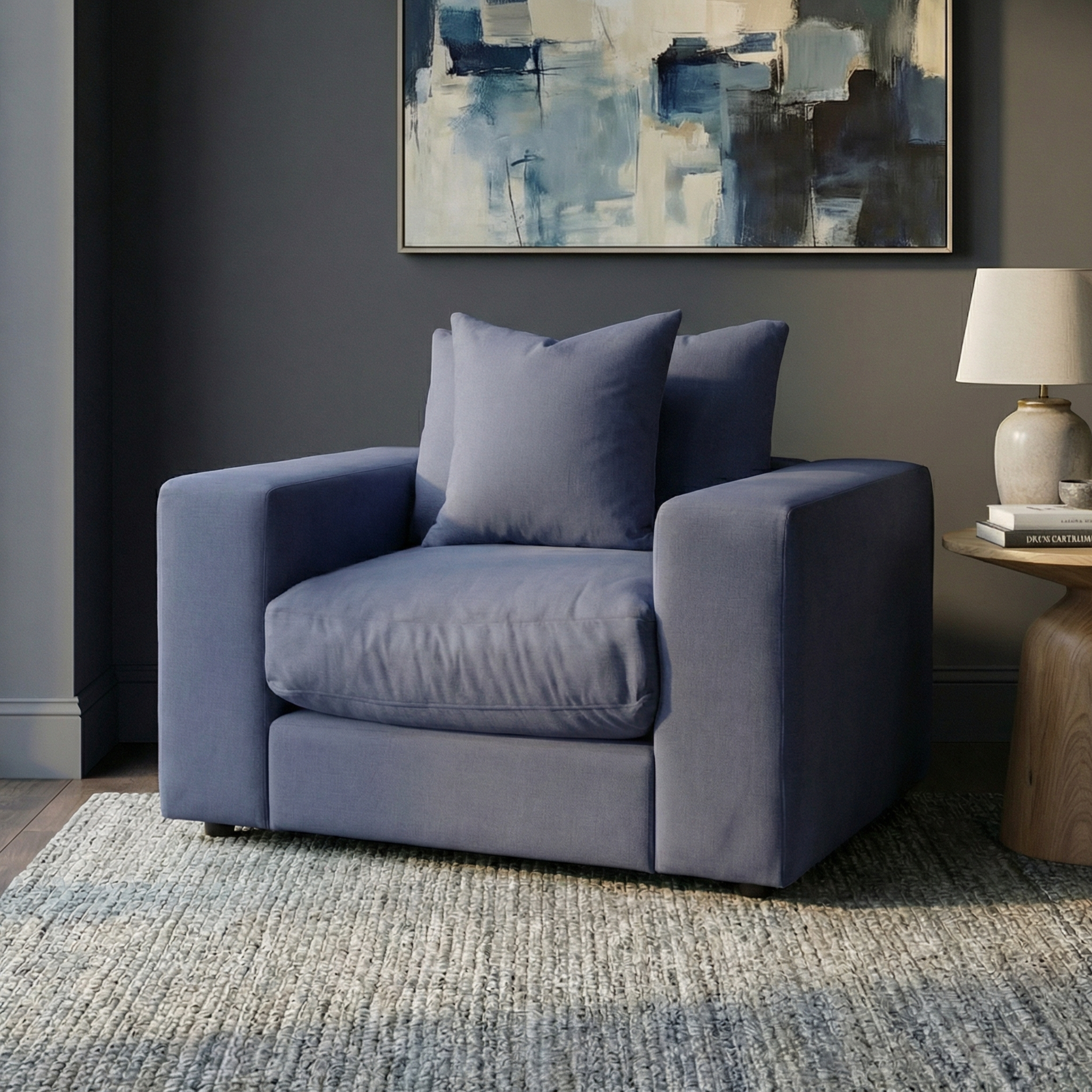 Hampshire Modular Armchair in Midnight Blue with duck feather and down cushions beside a round wooden table and lamp, beneath an abstract painting.