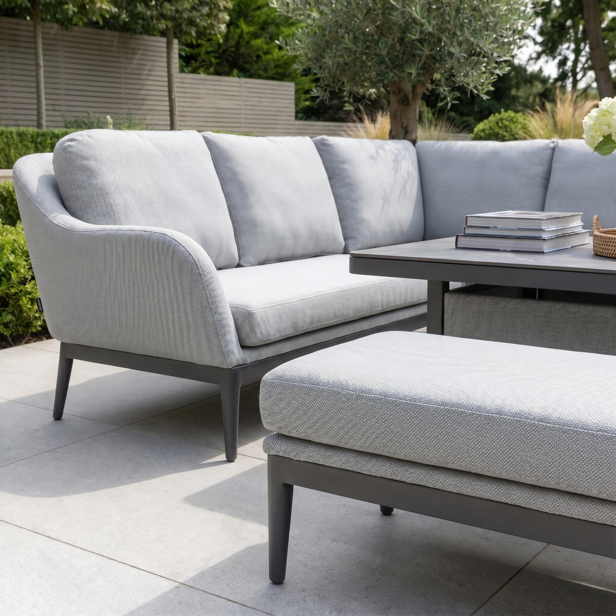 The Luna Outdoor Fabric Rectangular Corner Dining Set with Rising Table in Oyster Grey (Left Hand) features light grey cushions and a dark rising table—a stylish, low-maintenance garden furniture option.