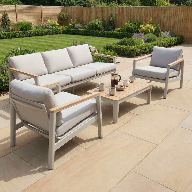 The Cora 3 Seat Sofa Set in Latte offers modern, weather-resistant garden furniture with a sofa, chairs, and table—perfect for a stone patio overlooking a lush garden.