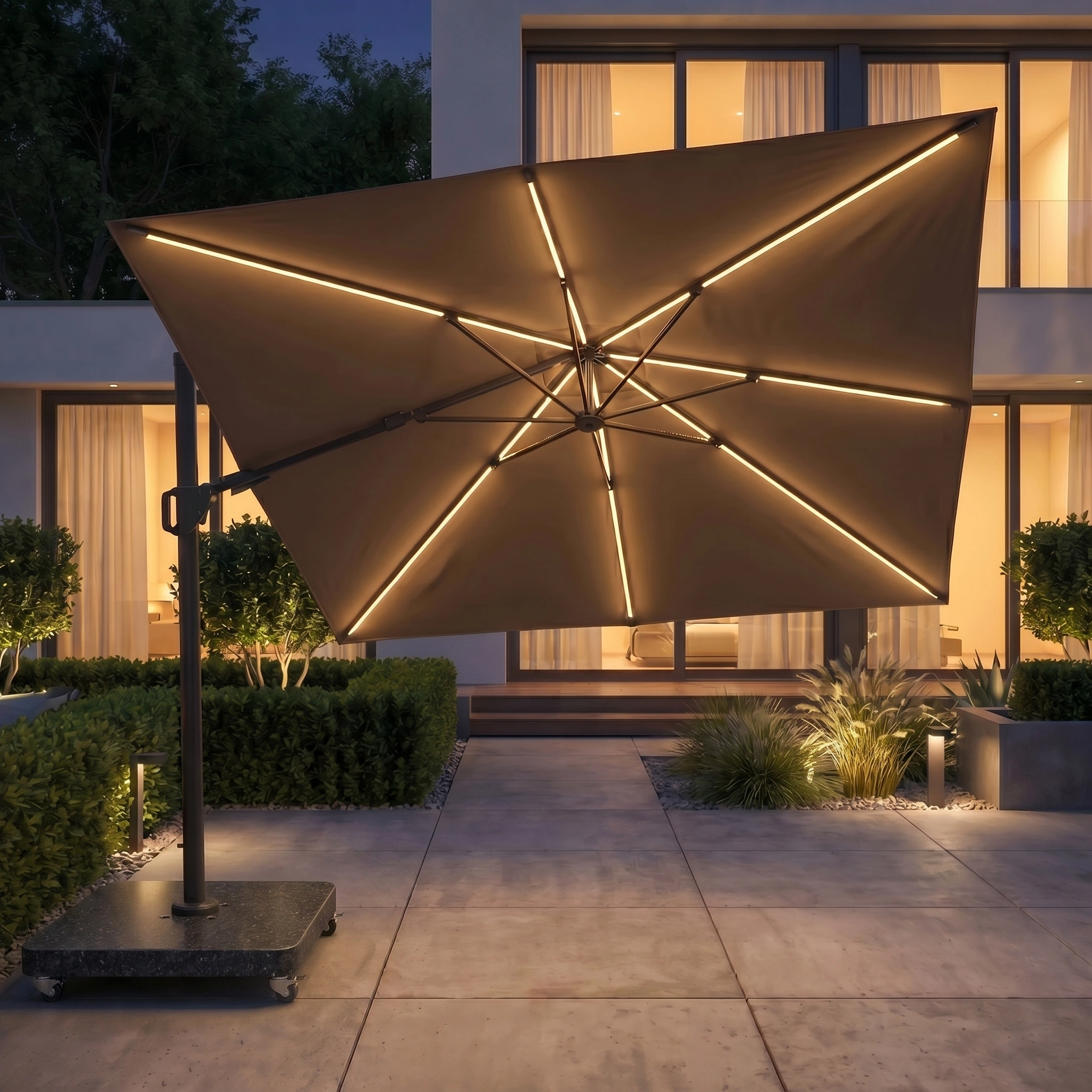 The Glow Challenger T2 3m Square Cantilever Parasol in Taupe, shown at dusk on a terrace, features glowing LED lights, a rechargeable system, sleek powder-coated aluminium frame, and includes a durable 90kg granite base.