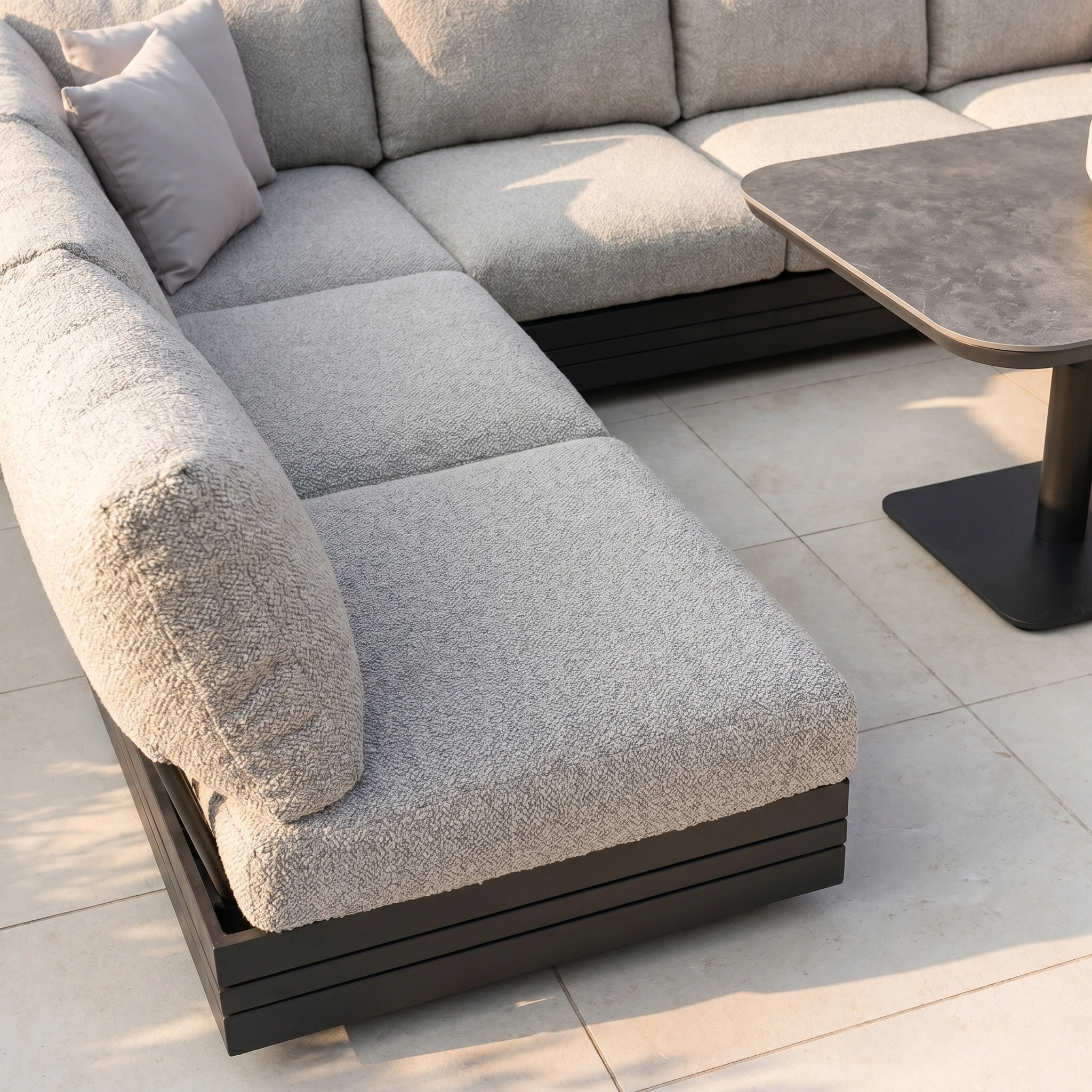 The Savona Luxury Outdoor Large U-Shape Corner Sofa Set in Truffle, paired with the Altura Rising Table, features grey upholstery and a rust-proof aluminium frame for modular durability and style on your patio.