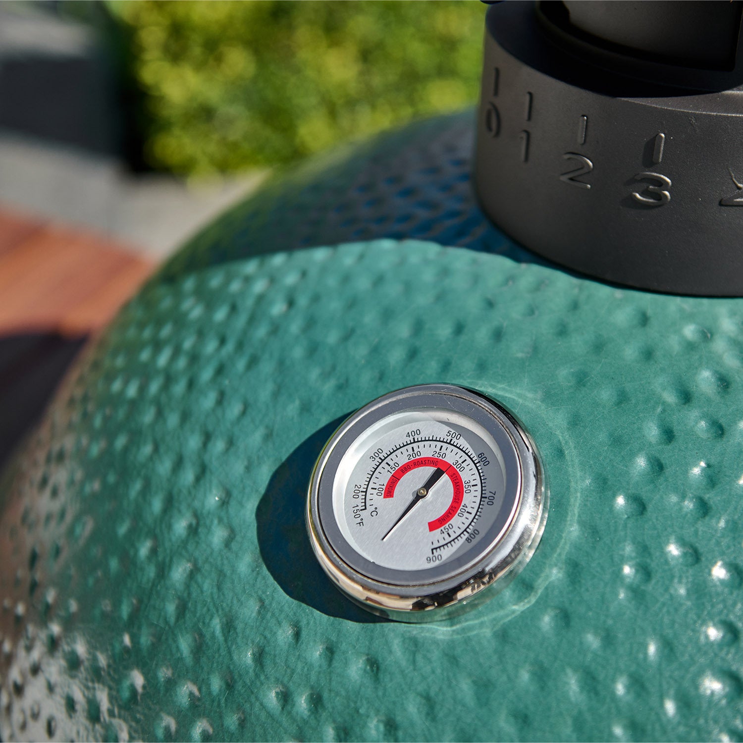 Close-up of the Kamado BBQ 22" Ceramic Grill in Matte Green, featuring a built-in thermometer displaying a temperature reading of approximately 450°F.