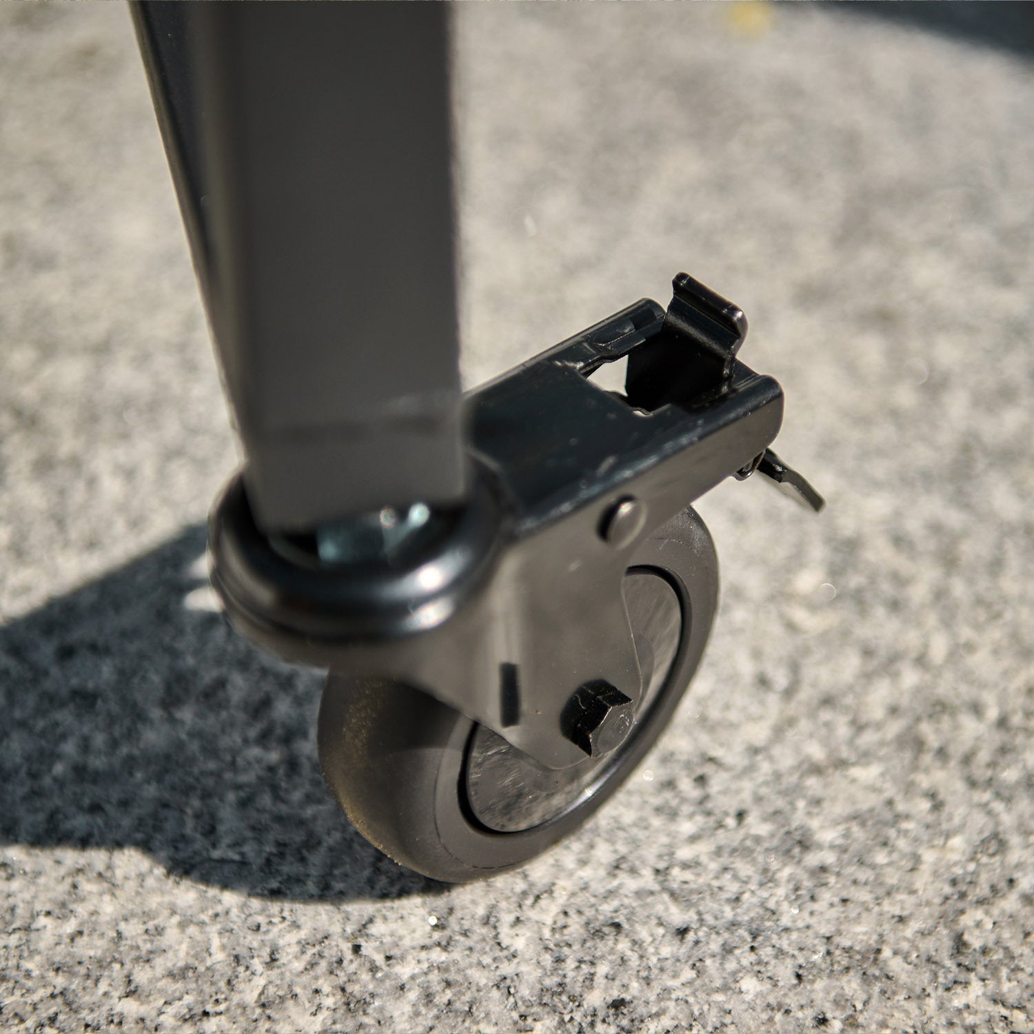 Close-up of a black caster wheel attached to a Kamado BBQ 22" Ceramic Grill in Matte Green, resting on a concrete surface.