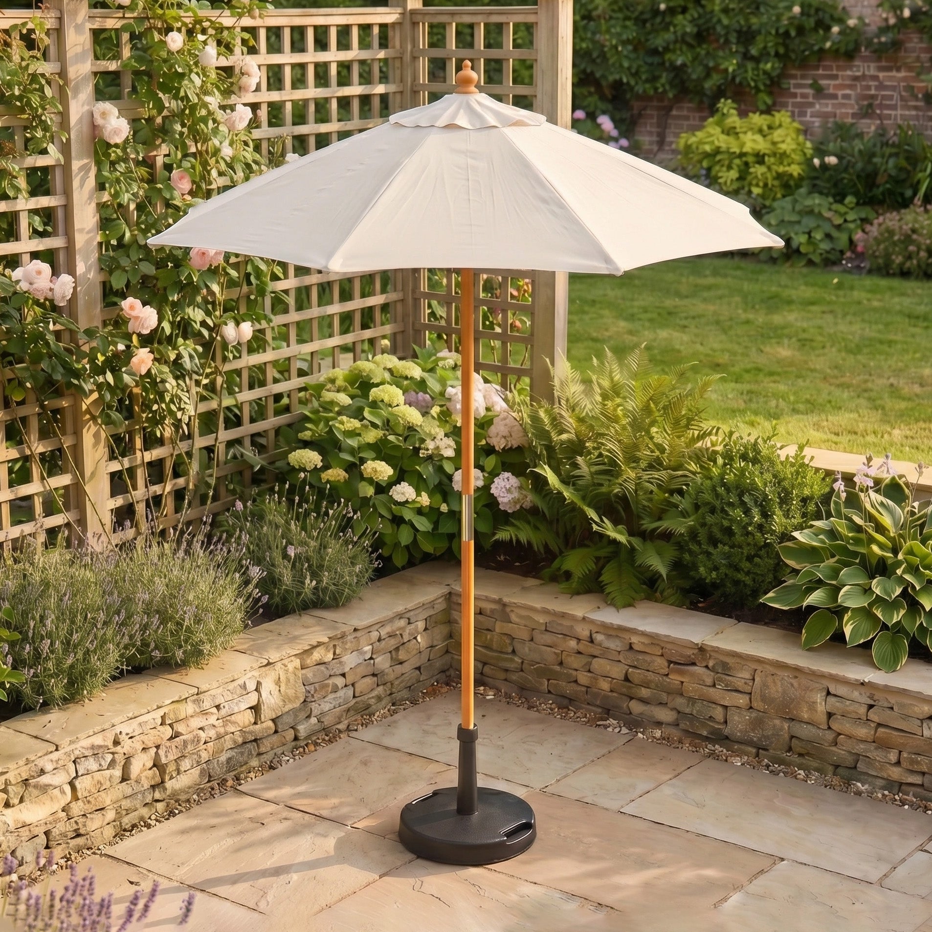 The Kratos 2m Round Wooden Parasol in Beige stands in a garden beside climbing roses and hydrangeas, providing stylish UV protection.