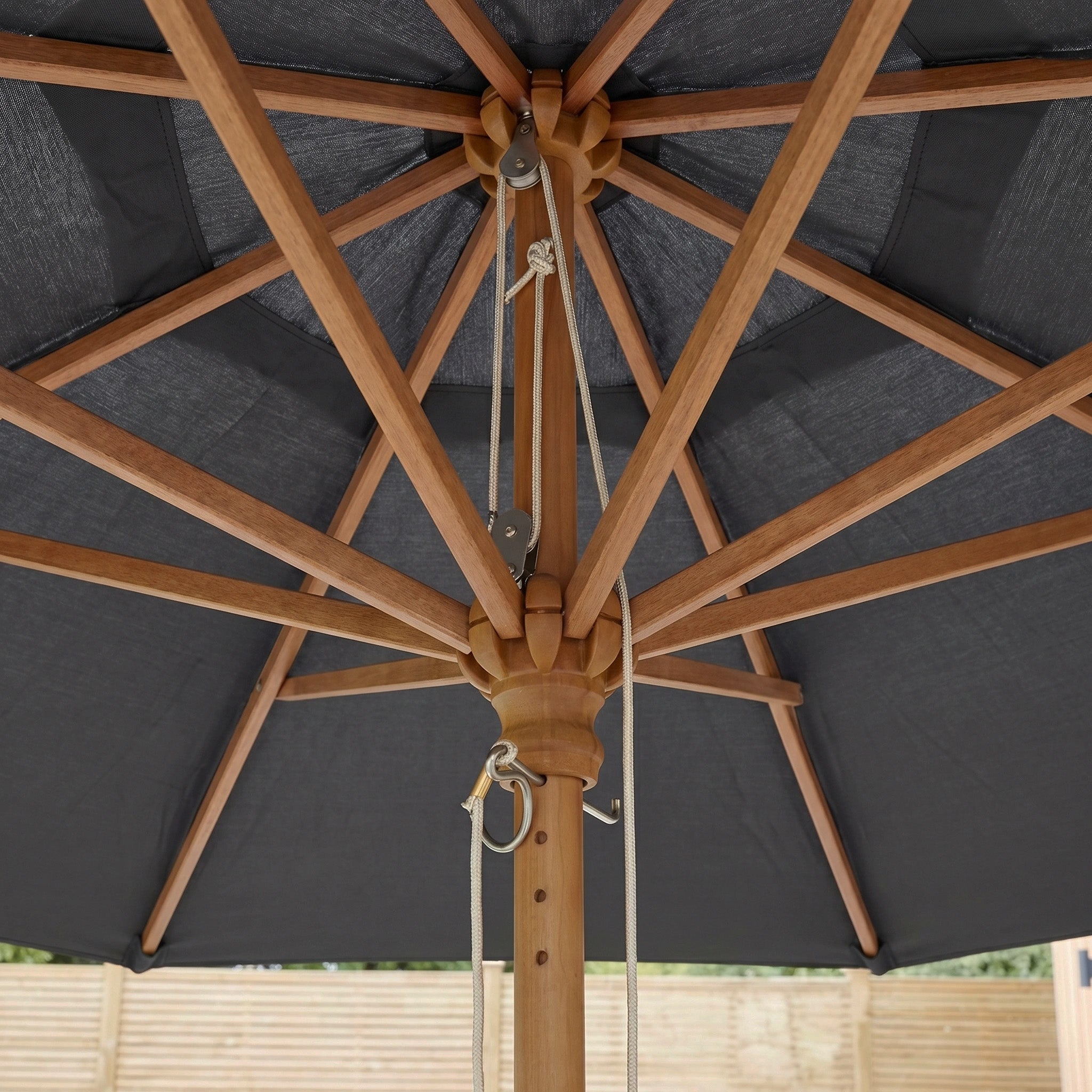 The Kratos 2m Round Wooden Parasol in Grey features a dark grey fabric, pulley system and rope, plus a UV 50+ rated sun protector for added safety.