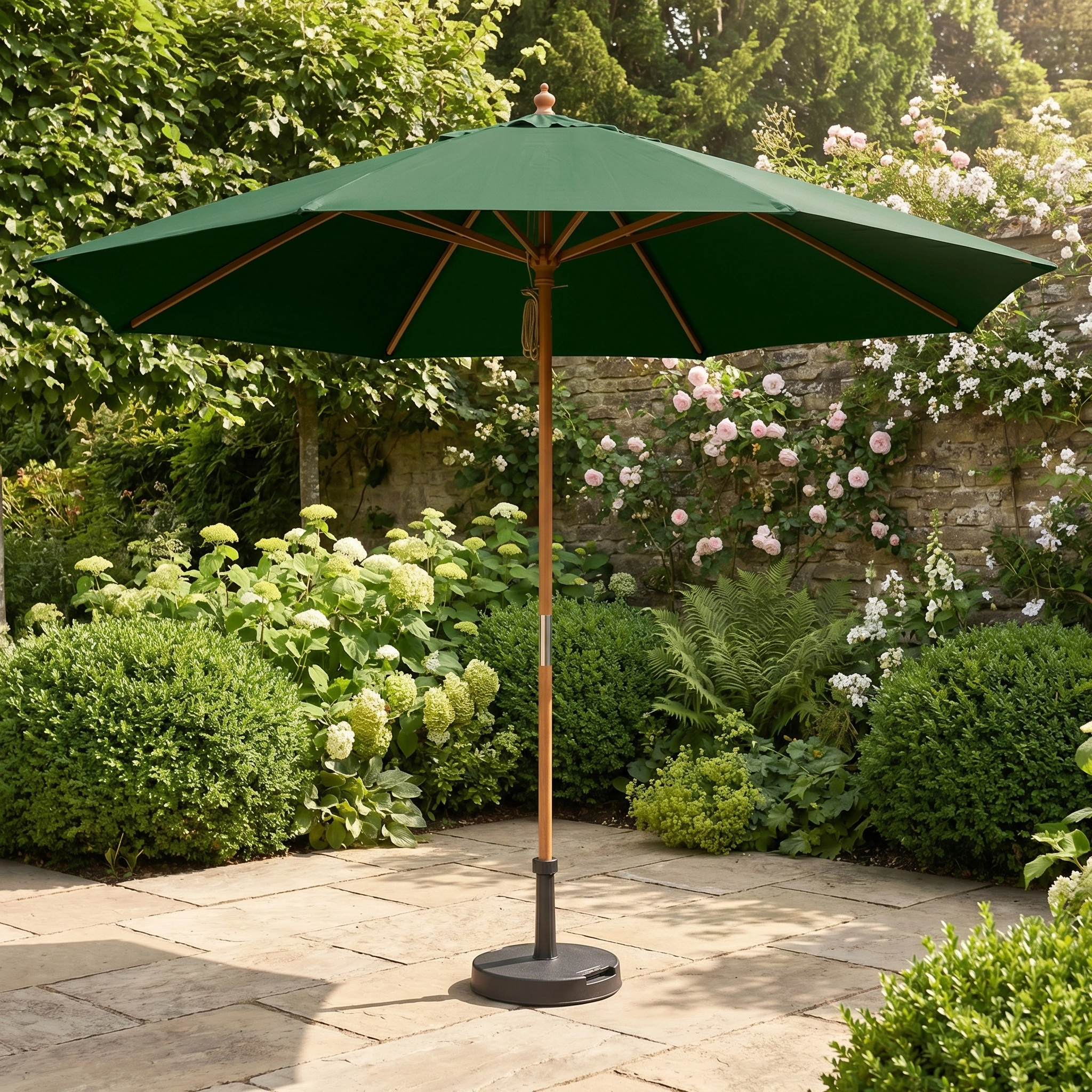 A Kratos 3m Round Wooden Parasol in Green stands on a stone terrace, surrounded by lush garden plants and blooming flowers. It offers elegant shade and reliable UV protection for your outdoor space.