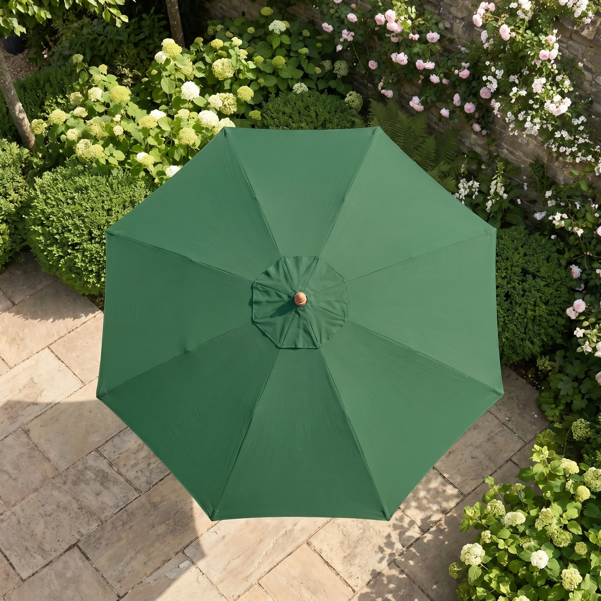 The Kratos 3m Round Wooden Parasol in Green provides stylish shade and UV protection, perfect for your garden or patio among stone paving and lush plants.