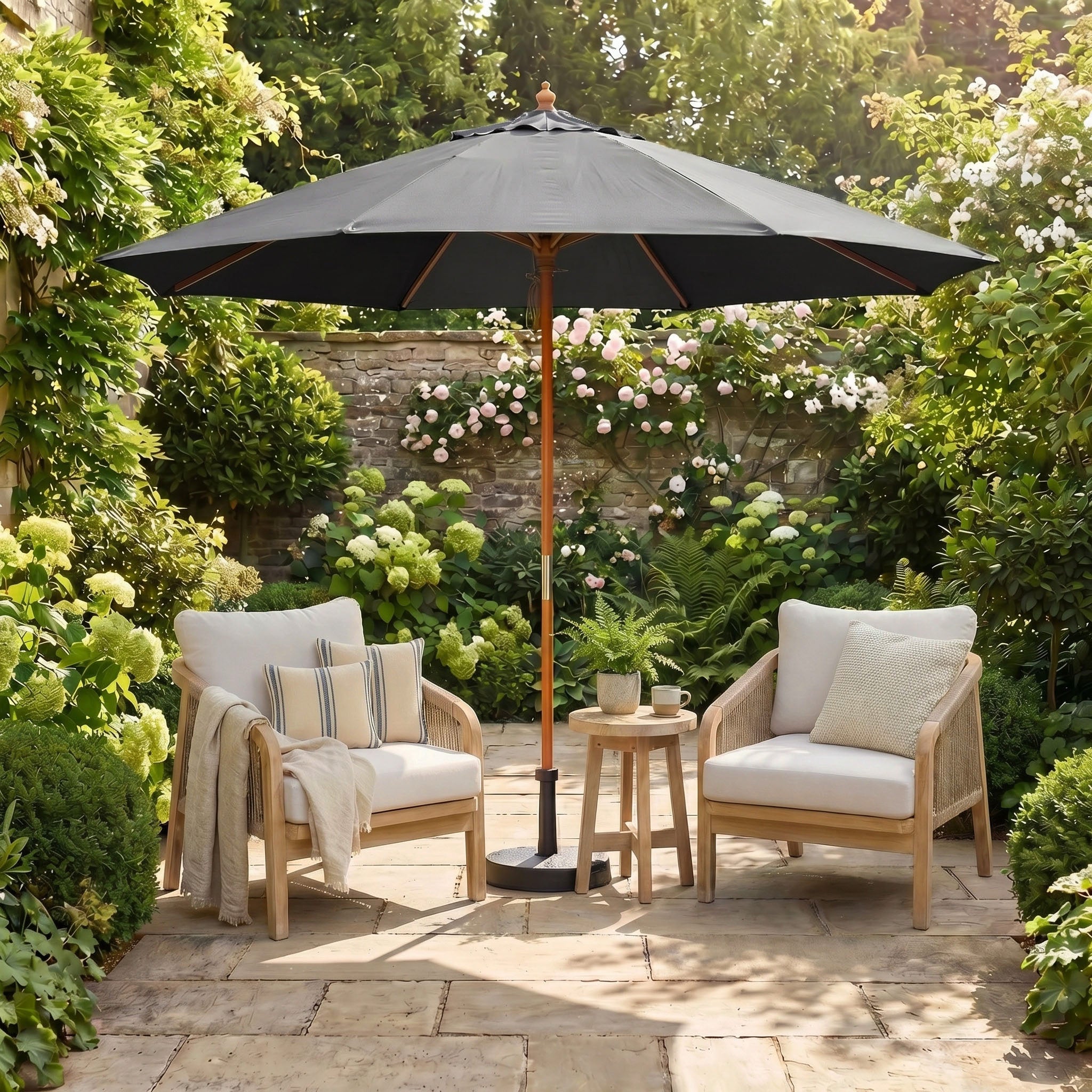 Two cushioned chairs and a side table sit under the Kratos 3m Round Wooden Parasol in Grey, offering UV protection in a lush garden patio setting.