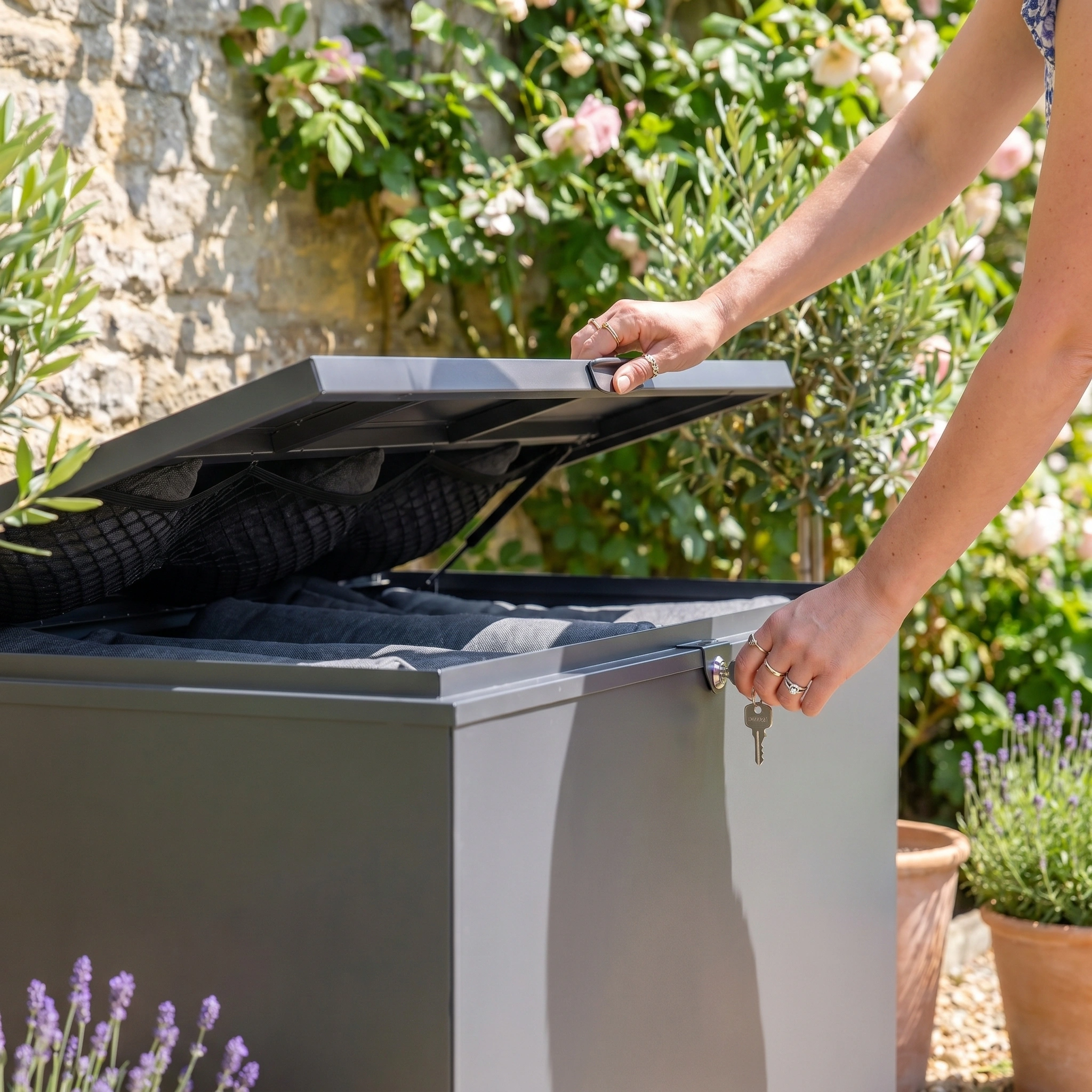 A person is locking the Large Storage Box in Grey, made of galvanised steel, with a key.