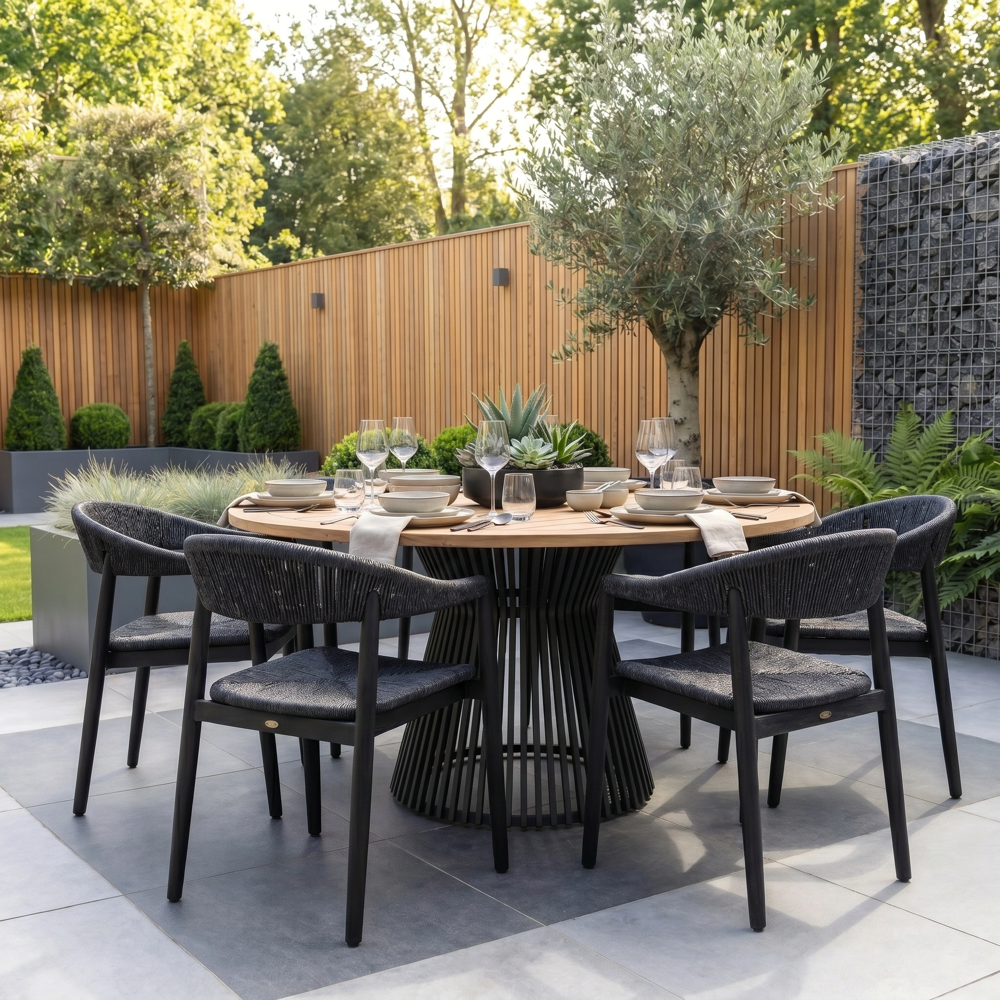 The Lucca 6 Seat Dining Set with Teak Round Table in Black is a modern outdoor dining set featuring a sleek teak top and black chairs, ideal for stylish garden patio gatherings.
