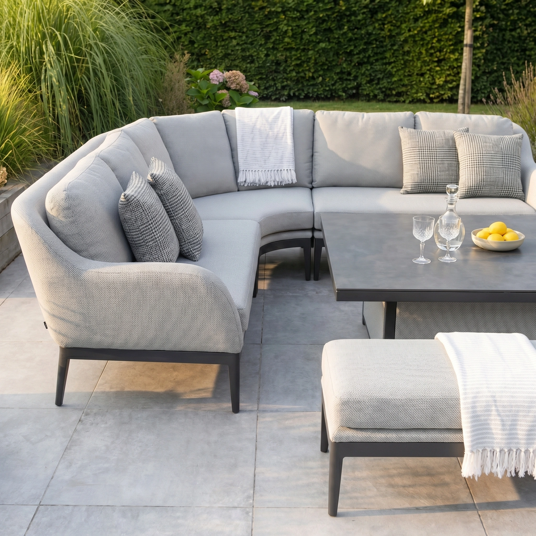 The Luna Deluxe Outdoor Fabric Square Corner Dining Set with Rising Table in Oyster Grey features cushioned seats, a versatile table, and plenty of space for outdoor dining and relaxation.