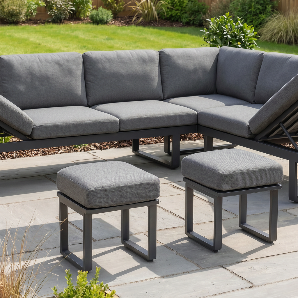 Modern garden furniture featuring the Lyra Corner Dining Set in Charcoal with gray cushions, a table set for four, and a lush green garden in the background.