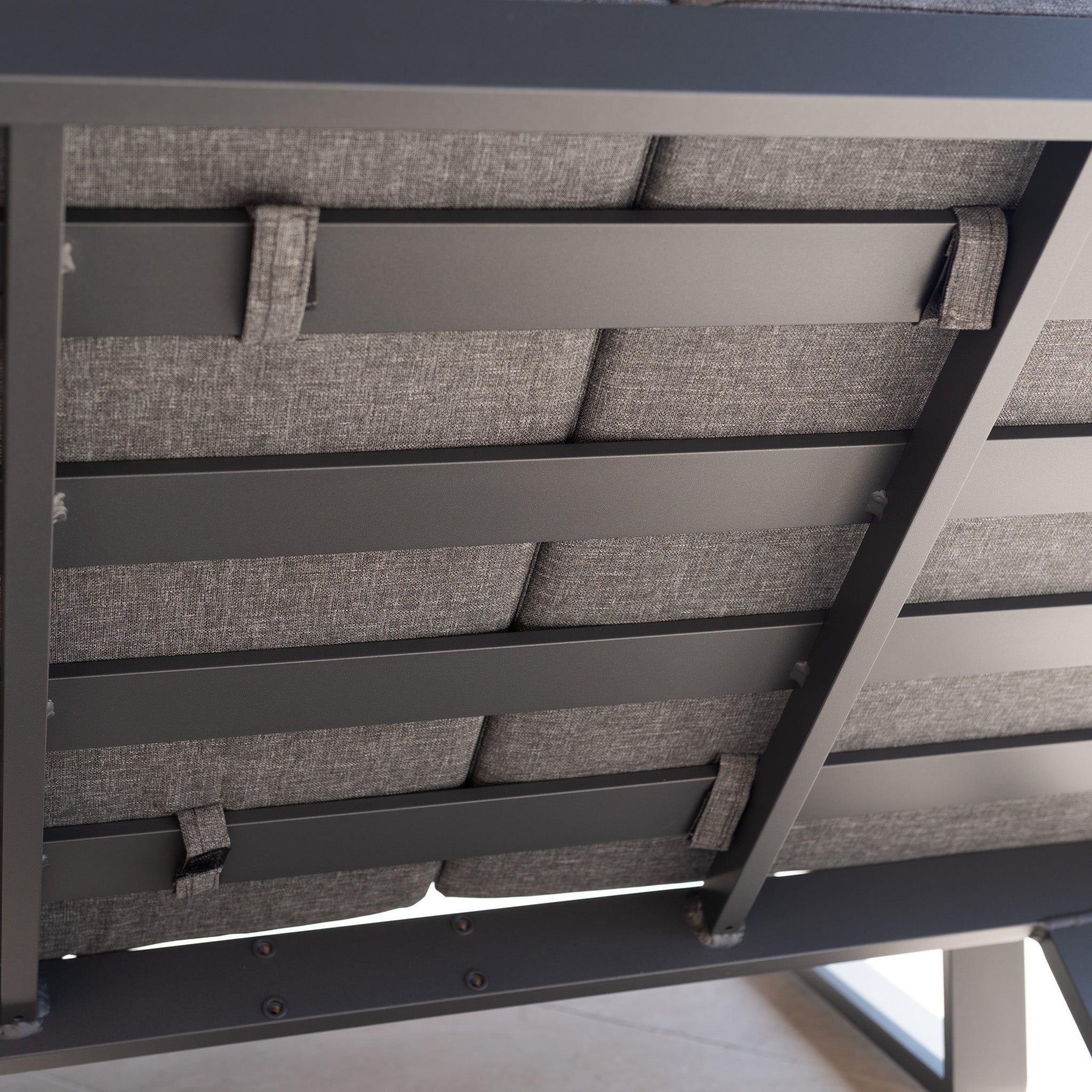 Close-up of the Lyra Corner Dining Set in Charcoal shows its cushioned bench underside, with a strong aluminium frame and fabric straps—perfect for modern outdoor dining.