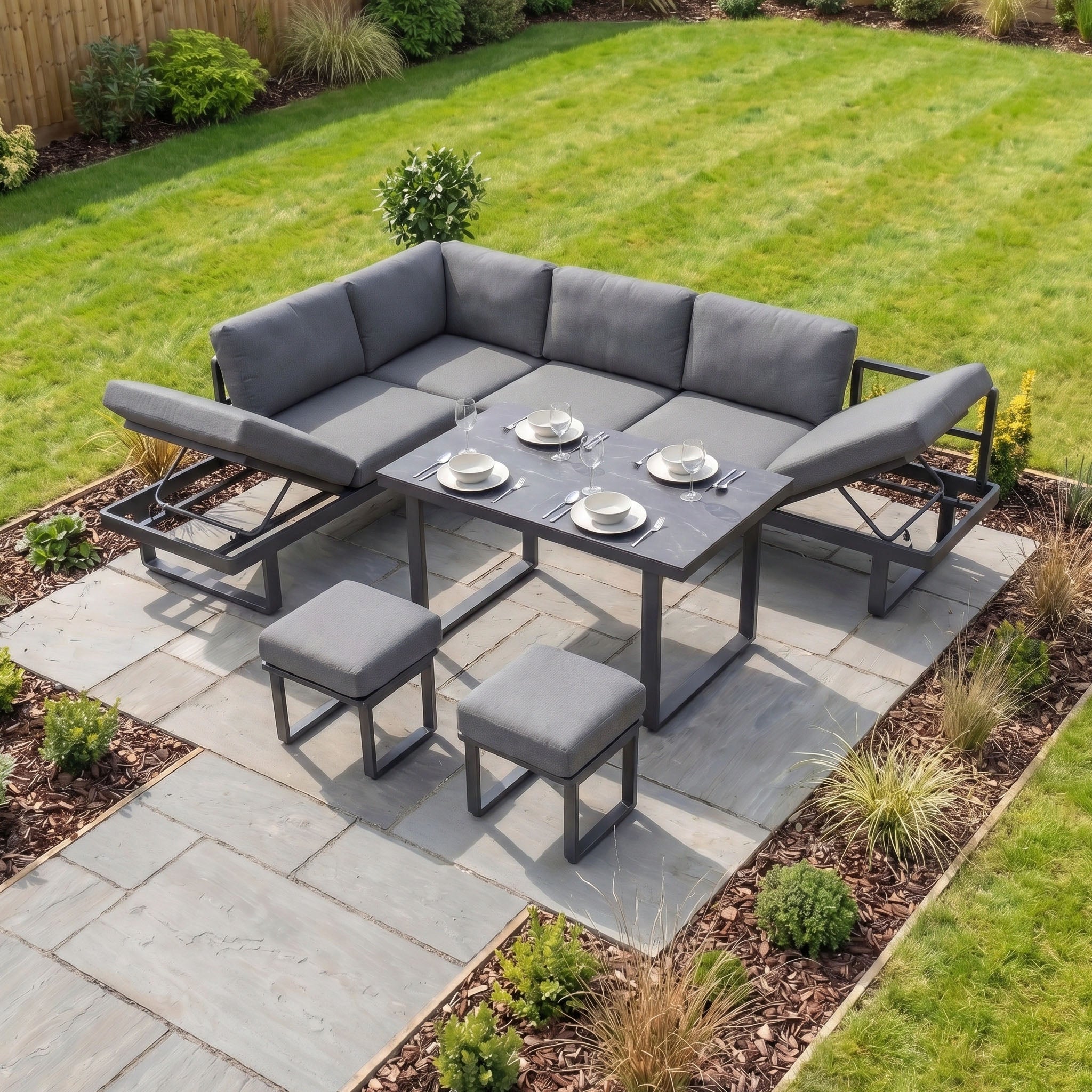 Modern outdoor garden furniture featuring the Lyra Corner Dining Set in Charcoal with gray cushioned seating, two stools, and a sturdy aluminium table for four—perfect for relaxing in your garden.
