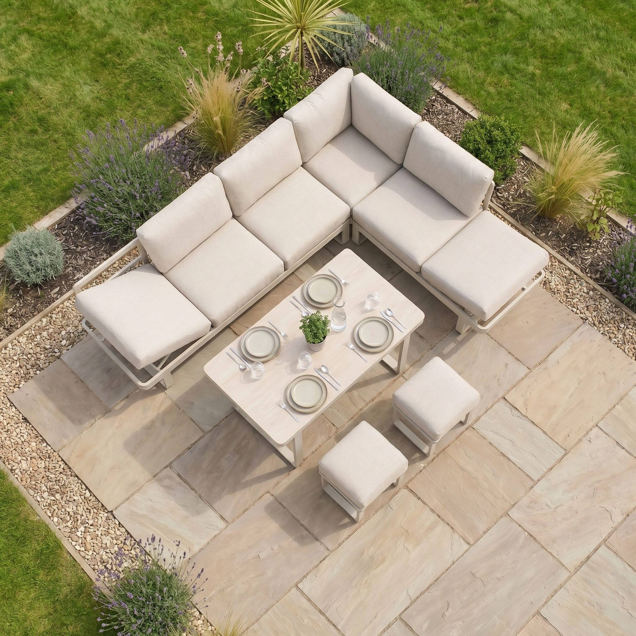 The Lyra Corner Dining Set in Latte, featuring an aluminium sofa and table, is ideal outdoor furniture for relaxed gatherings on a stone patio amid grass and garden plants.