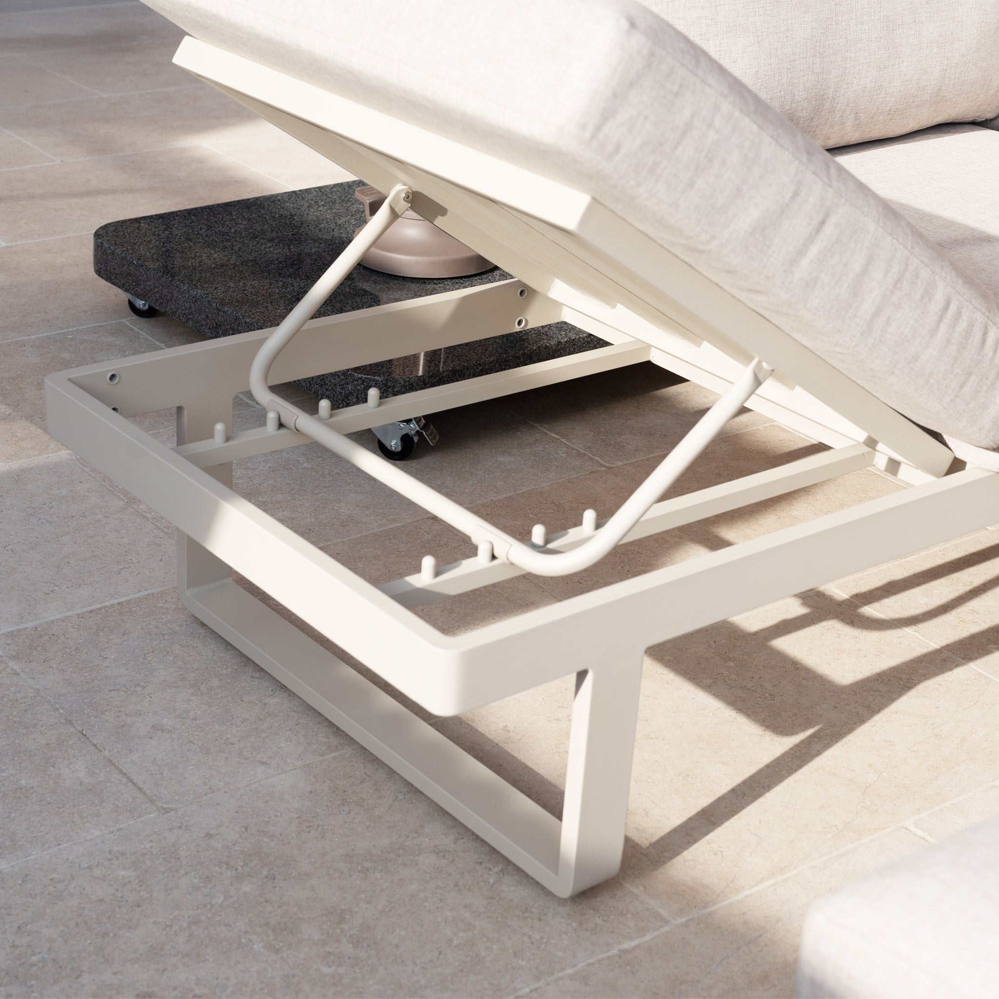 A close-up of an adjustable lounge chair with a metal frame from the Lyra Corner Dining Set in Latte, shown on a sunlit tiled floor.
