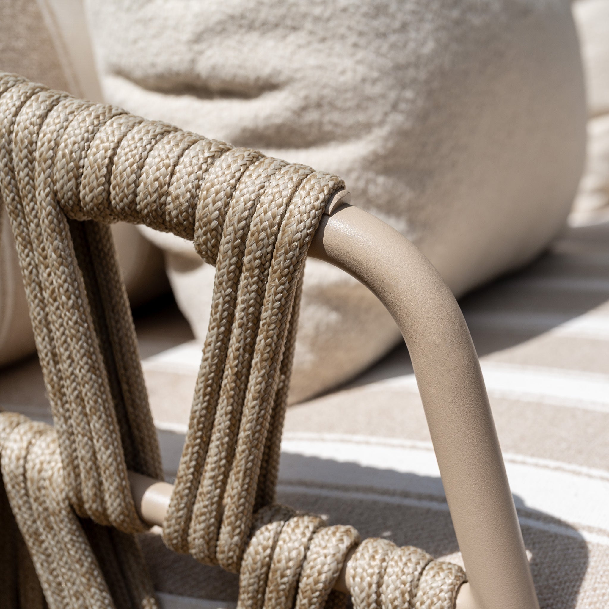 Closeup of the Madeira 3 Seat Sofa in Striped Latte (Ex Display), featuring a beige rope-wrapped frame, a soft, textured pillow, and elegant striped fabric in the background—an exquisite example of garden furniture.