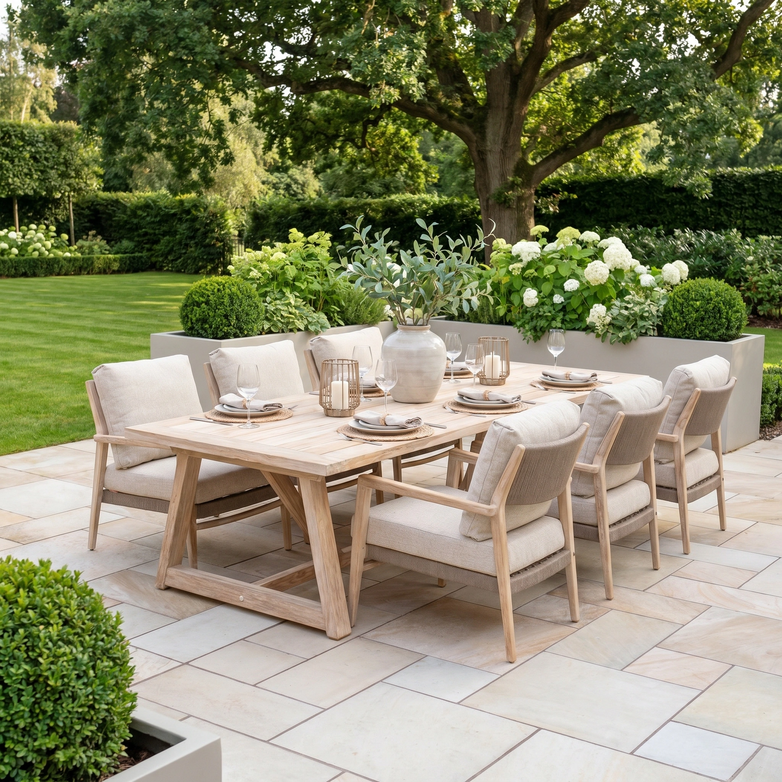 The Noah 6 Seat Low Rectangular Dining Set in Volga Grey includes six cushioned chairs, perfect for outdoor dining on a patio surrounded by greenery.