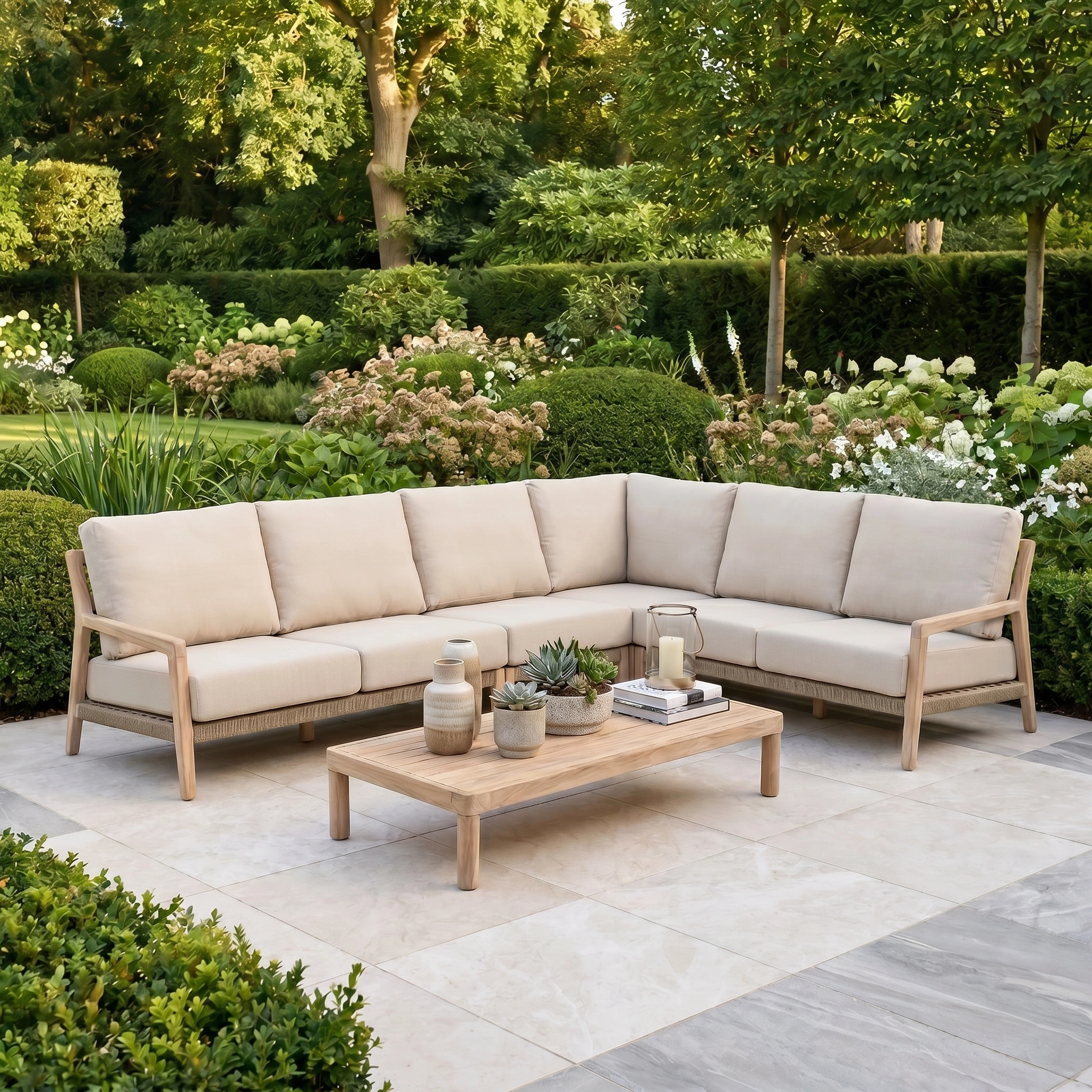 Noah Corner Sofa Set in Volga Grey with wooden coffee table on a patio, surrounded by lush green landscaping—a modern garden sofa set paired with elegant teak outdoor furniture.