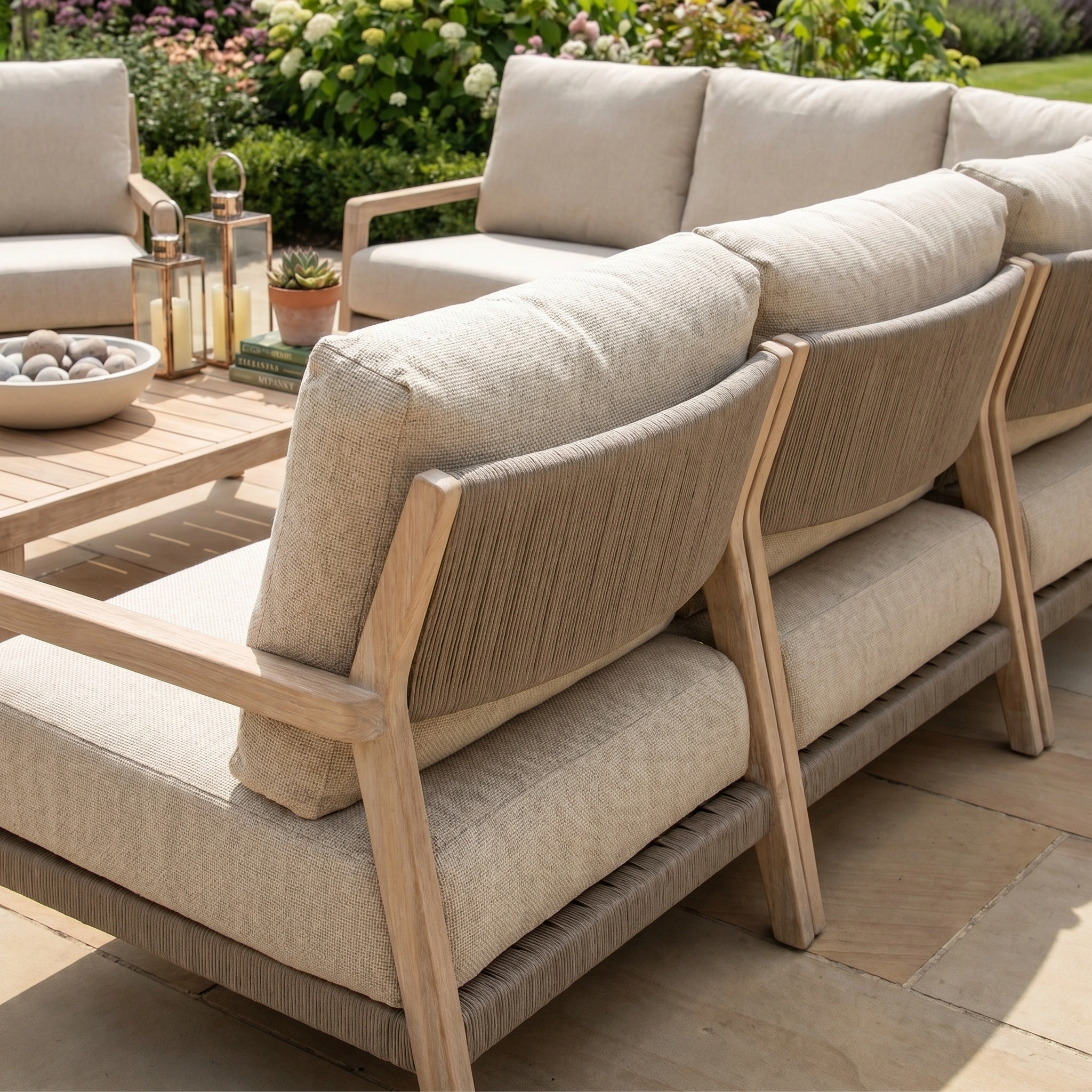 The Noah Corner Sofa Set with Armchair in Volga Grey creates stylish garden seating on the patio, surrounded by lush plants and decorative lanterns on the table.