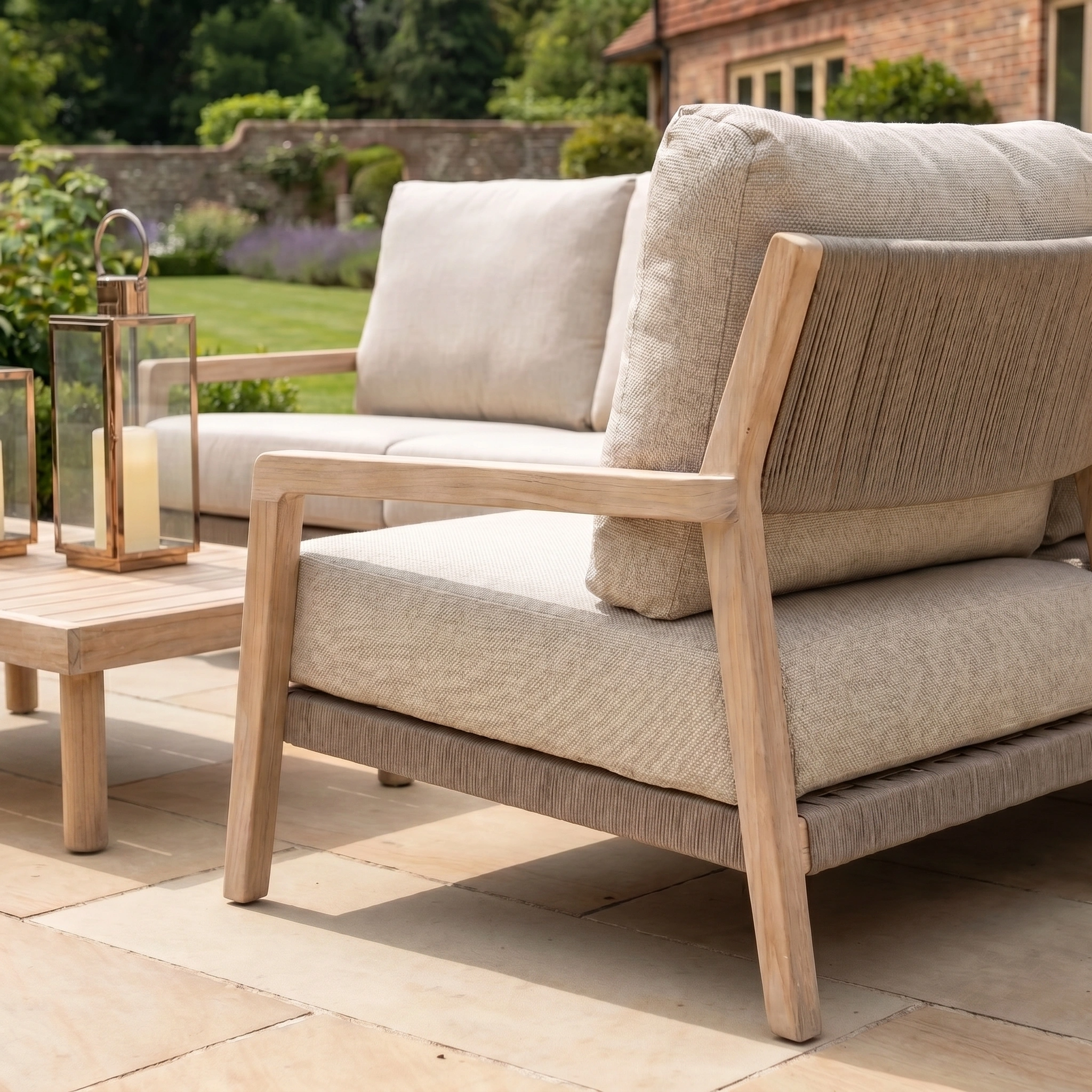 Outdoor patio with the Noah Corner Sofa Set with Armchair in Volga Grey, complemented by a wooden coffee table and brass lanterns, creating a cozy garden setting.
