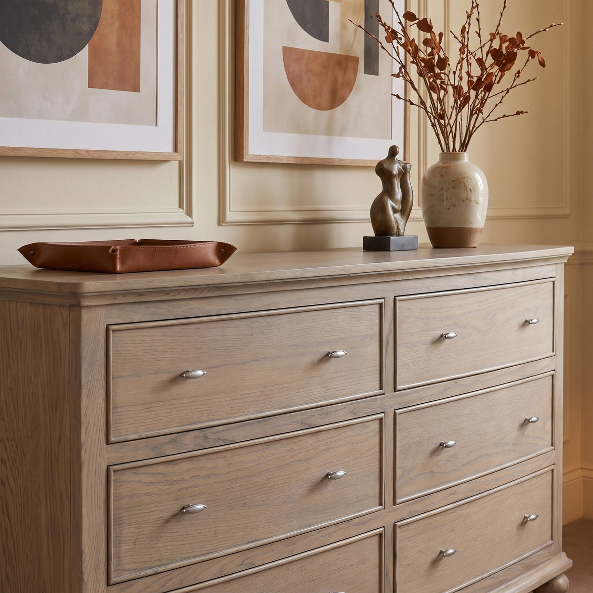 a dresser with a vase of flowers and a statue on top
