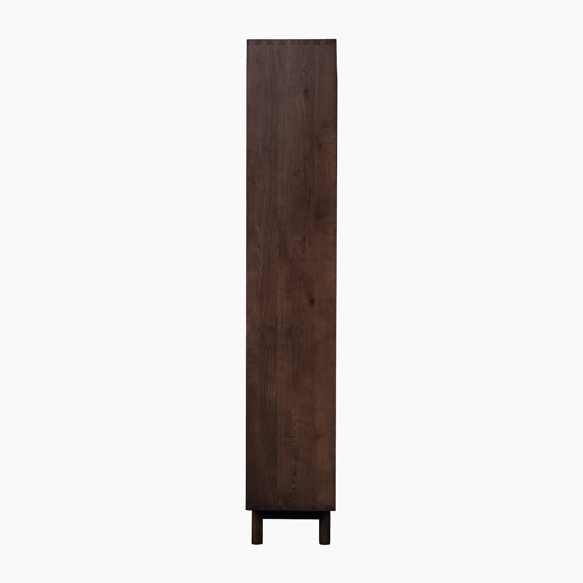 Tall, narrow Oslo Bookcase in Walnut shown from the side, standing on short legs against a white background—this piece features clean lines and elegant simplicity.