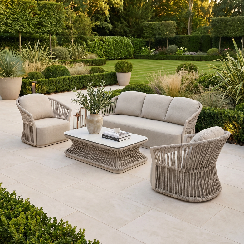 Outdoor patio featuring the Pello 3 Seat Sofa Set in Fawn, beige wicker furniture with quick-dry cushions, a coffee table, and a lush green garden in the background.