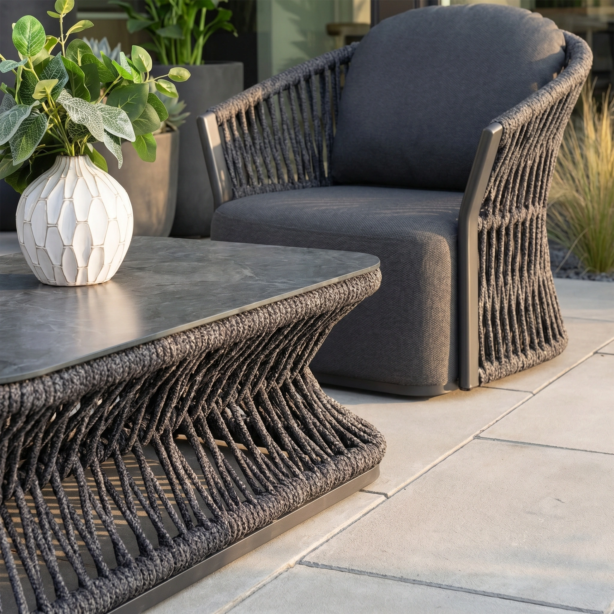 The Pello 3 Seat Sofa Set in Grey features modern garden furniture with a woven rope design, low table, white vase with green plant, and quick dry cushions for comfort and convenience.