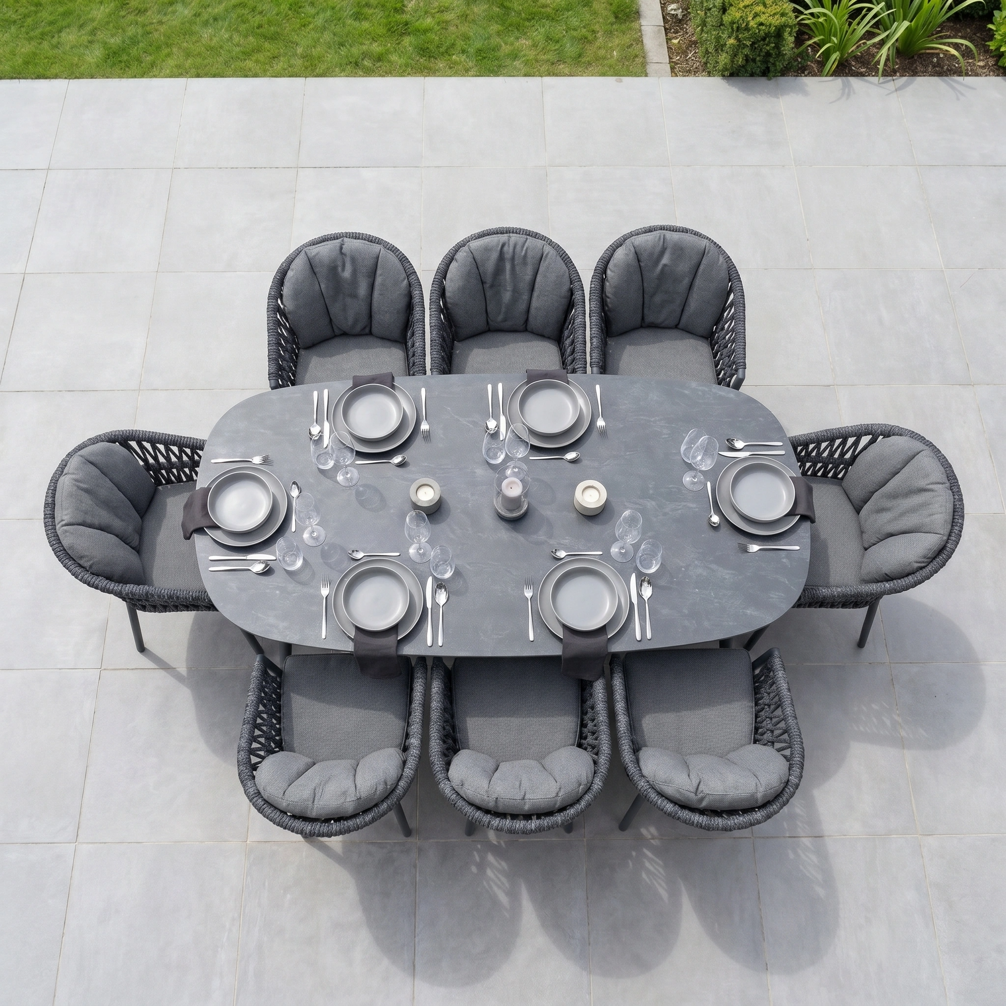 The Pello 8 Seat Oval Dining Set with Ceramic Table in Grey features cushioned chairs and offers weather-resistant elegance, complete with plates, cutlery, and glasses—perfect for stylish outdoor gatherings.