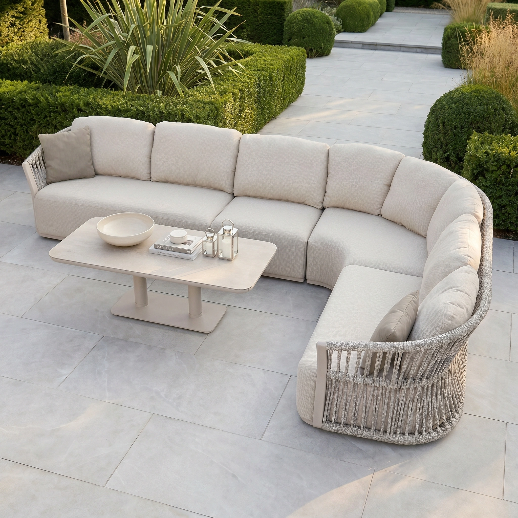 Pello Deluxe Curved Sofa Set with Altura Rising Table in Fawn features quick dry cushions—ideal for stylish outdoor relaxation on your patio, surrounded by greenery.