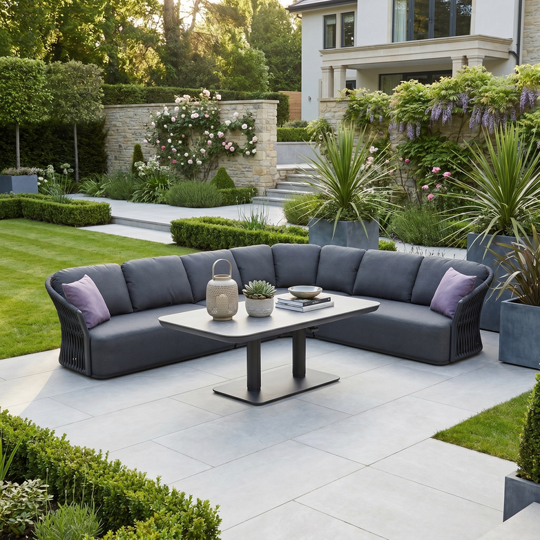The Pello Deluxe Curved Sofa Set with Altura Rising Table in Grey features gray cushions and purple pillows, making a stylish garden dining set for outdoor furniture lovers on any landscaped patio.