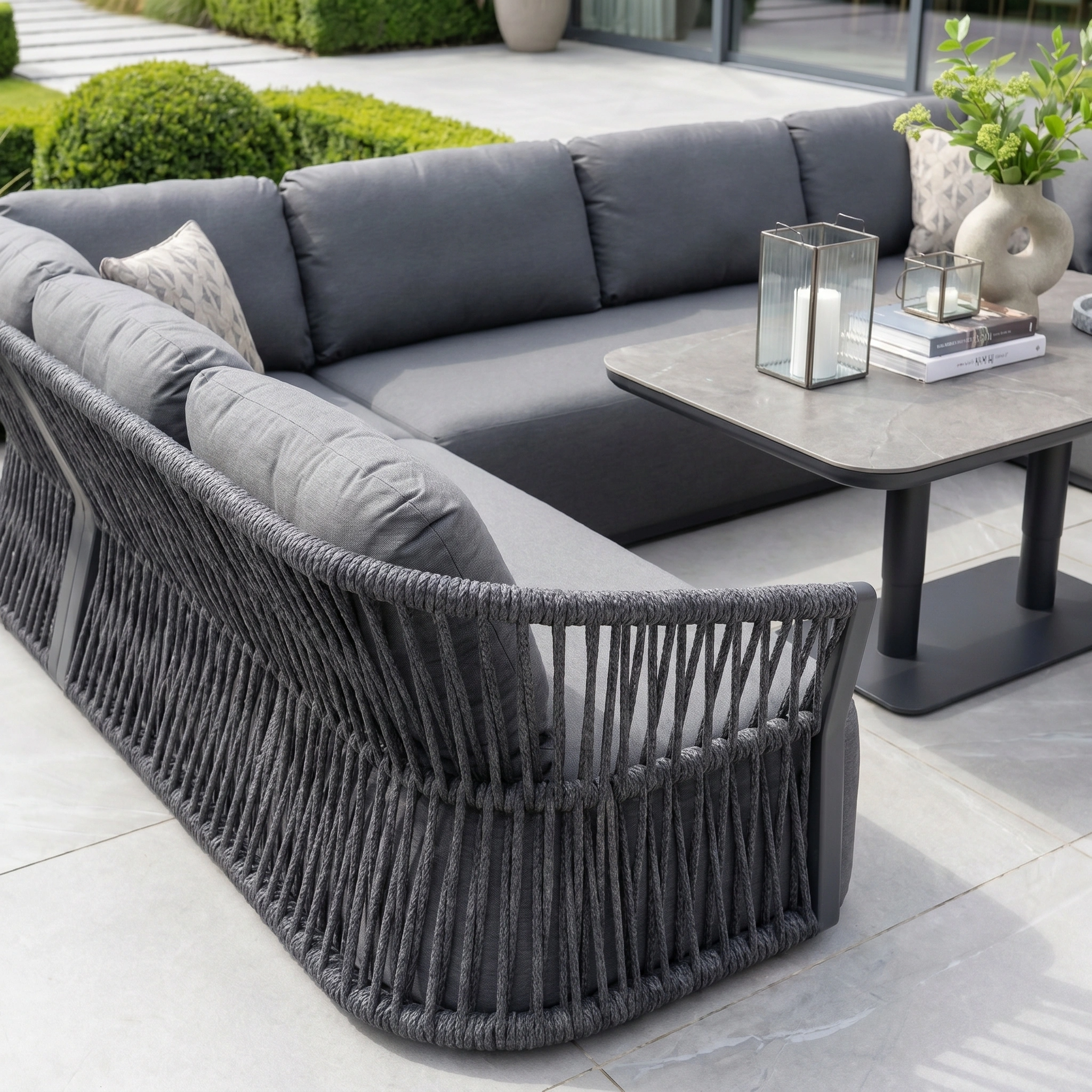 Modern outdoor patio featuring the Pello U-Shape Corner Sofa Set with Altura Rising Table in Grey, comfortable cushions, and stylish decorative lanterns and vases.