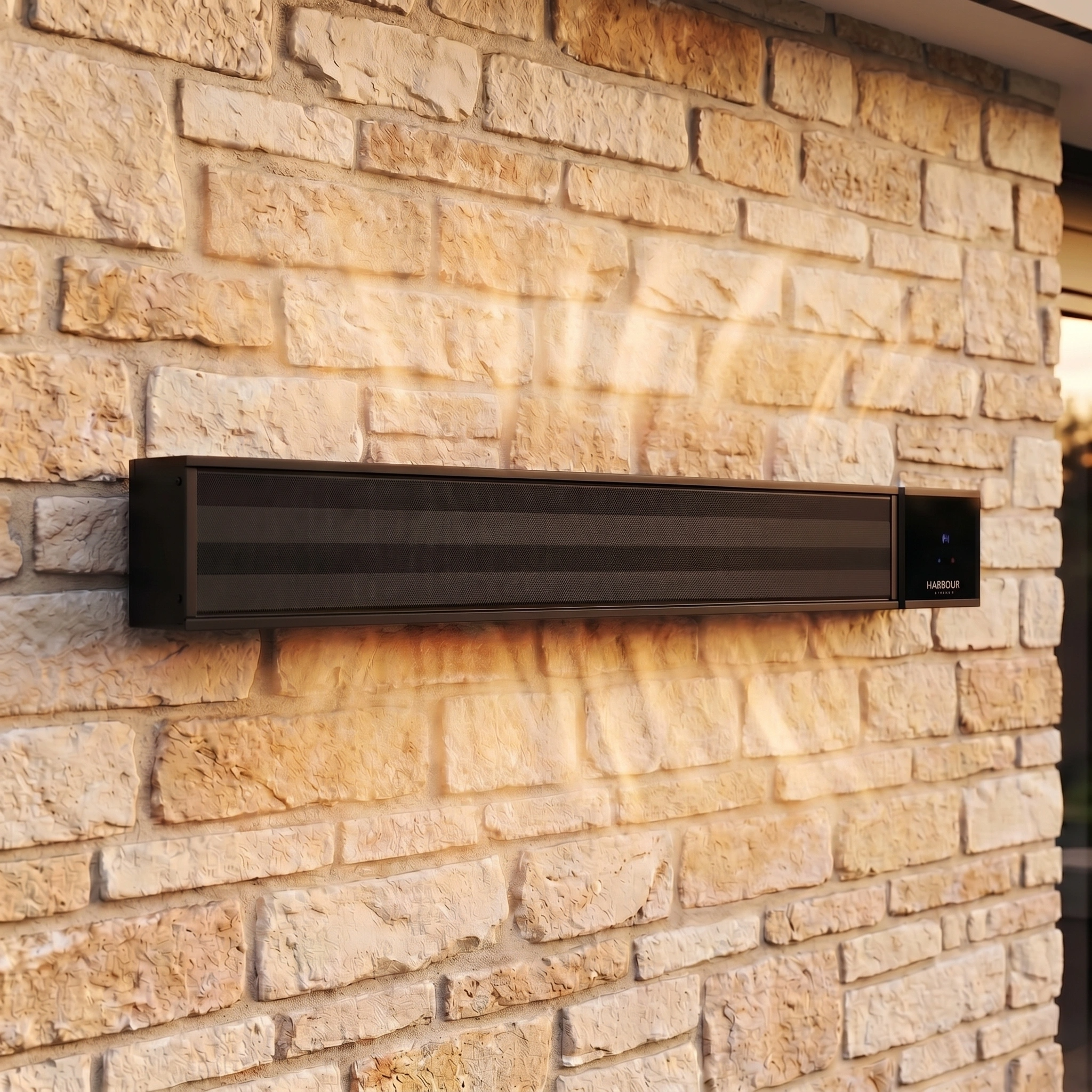 The PergoSTET 2400W Wifi & Bluetooth Heater in Black from Harbour Lifestyle emits warm air against a light brick outdoor wall, delivering stylish heating ideal for patios and pergolas.