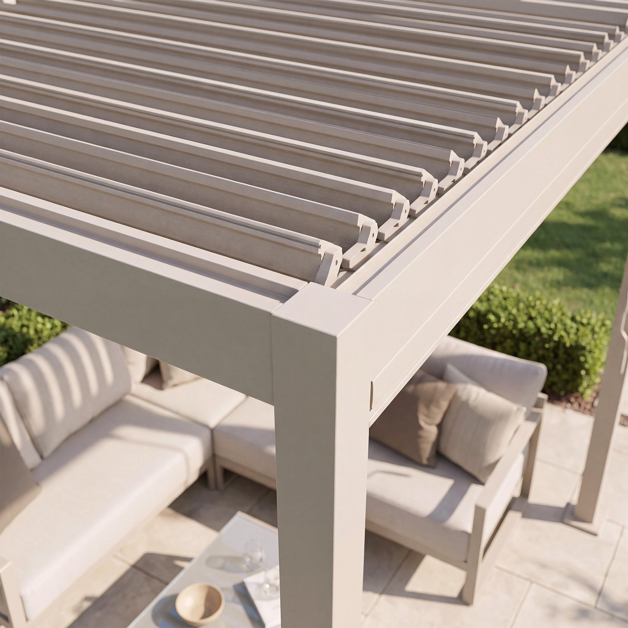 The PergoSTET Lite 2.4m x 3m Metal Rectangular Pergola in Latte features tilting louvres for adjustable shade, offering an elegant outdoor shelter over patio furniture in a sunny, landscaped backyard.