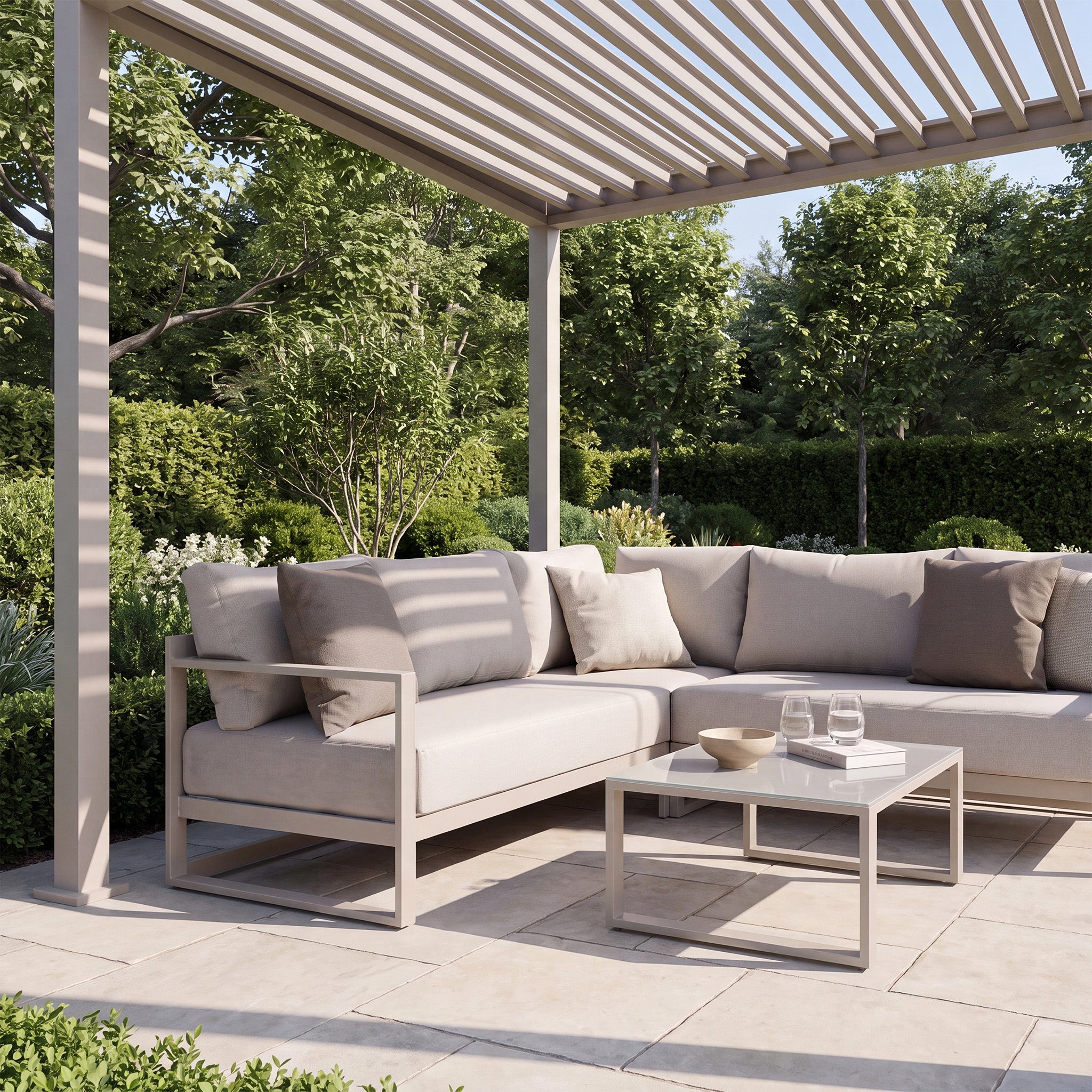 Modern outdoor patio with a beige sectional sofa, coffee table, and the PergoSTET Lite 2.4m x 3m Metal Rectangular Pergola in Latte featuring tilting louvres, surrounded by lush greenery.