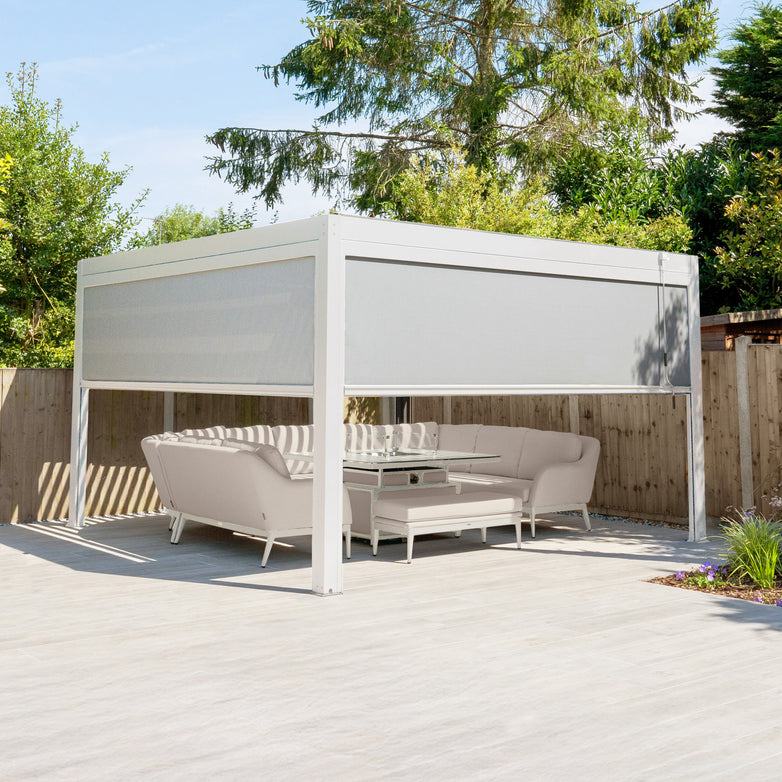 The PergoSTET Plus 4m x 4m Square Pergola in Latte, with 3 manual side blinds and LED lighting, provides shade for your patio sofas and table, making a stylish garden retreat.