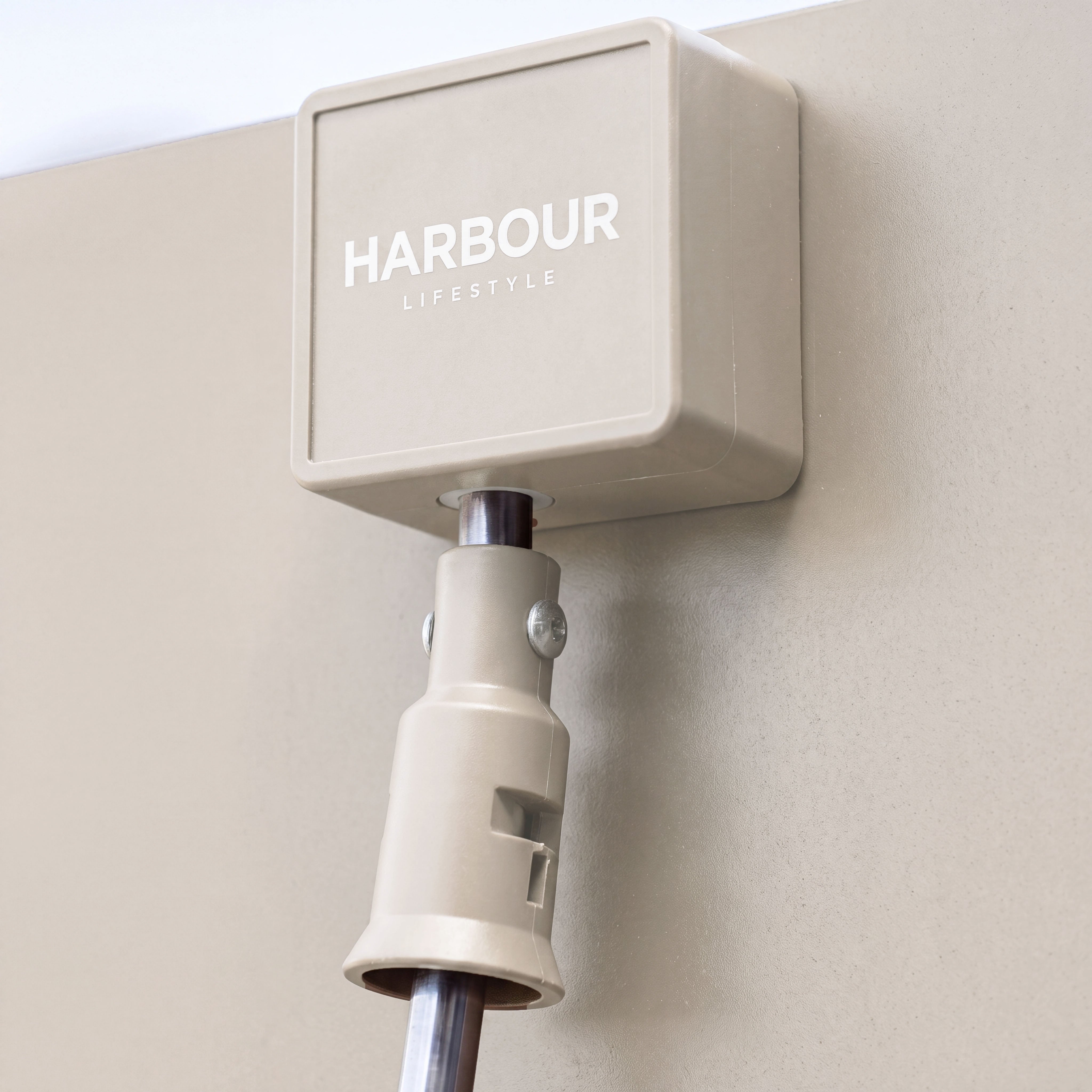 A beige electrical box is mounted on a wall with a cable attached at the bottom, making it ideal for use beneath the PergoSTET Lite 2.4m x 3m Metal Rectangular Pergola in Latte, or any outdoor shelter with tilting louvres.