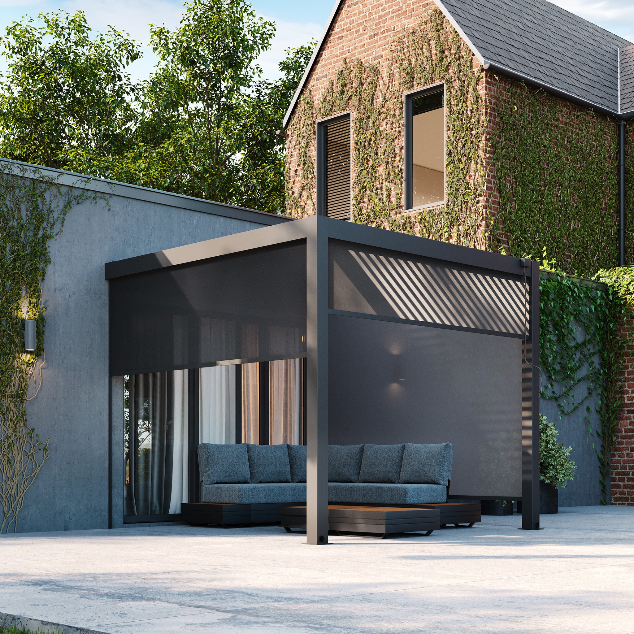 Modern patio with a PergoSTET Plus 3m x 3m Square Wall Mounted Pergola, featuring LED lighting and 3 drop sides in grey, along with sofas, adjacent to a house with ivy-covered walls and large windows.