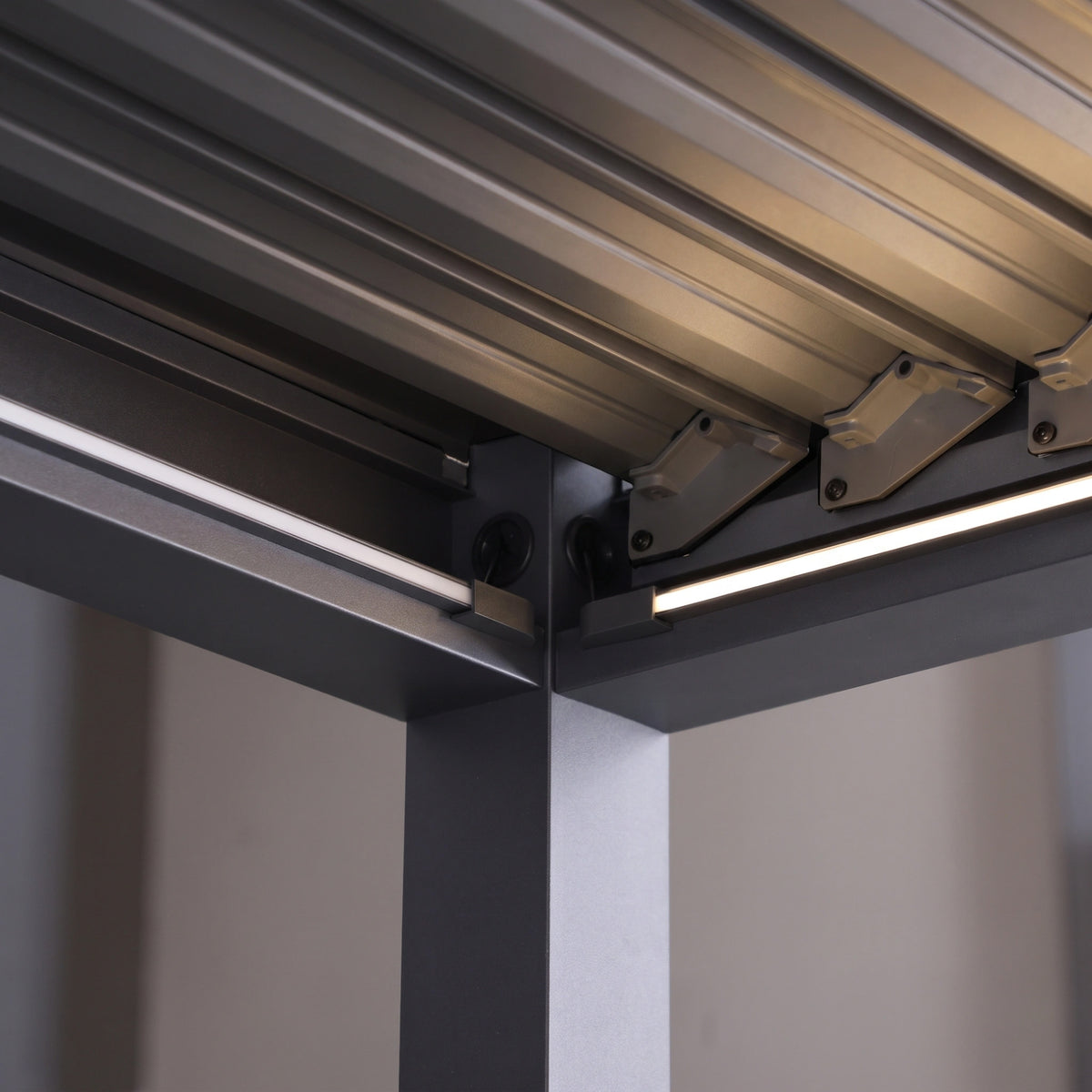 Close-up of the PergoSTET Lite 3m x 4m Metal Rectangular Pergola in Grey, featuring motorised louvres with adjustable panels, supporting beams, and integrated LED lighting.