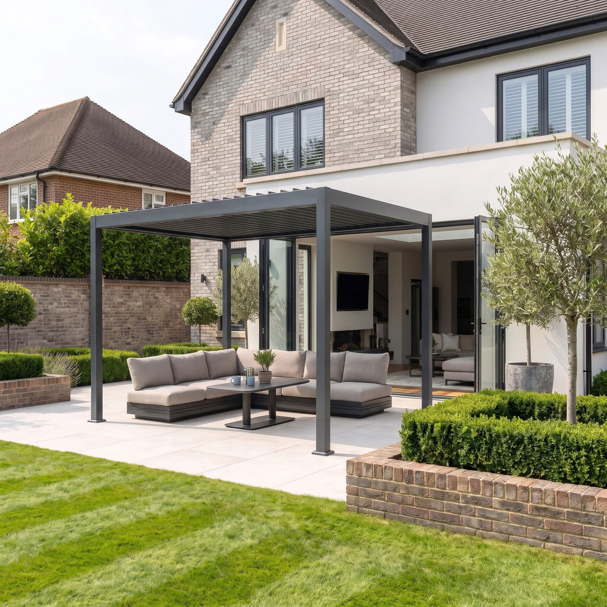 In the backyard of a contemporary house, a modern patio showcases the PergoSTET Lite 3m x 4m Metal Rectangular Pergola With Motorised Louvres and LED Lighting in Grey, complemented by outdoor sofas and a coffee table.