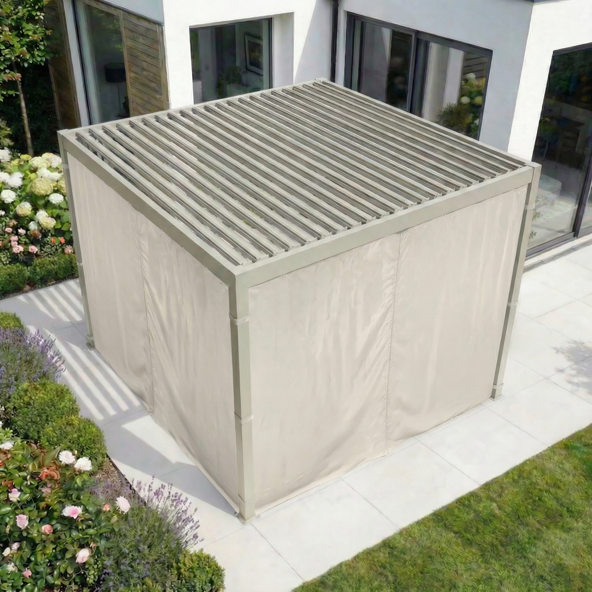 A sleek 3m x 3m Square Pergola with PergoSTET Side Curtains for Lite and Lite Neo in Latte enhances the patio by the white house, delivering stylish privacy and all-weather outdoor comfort.