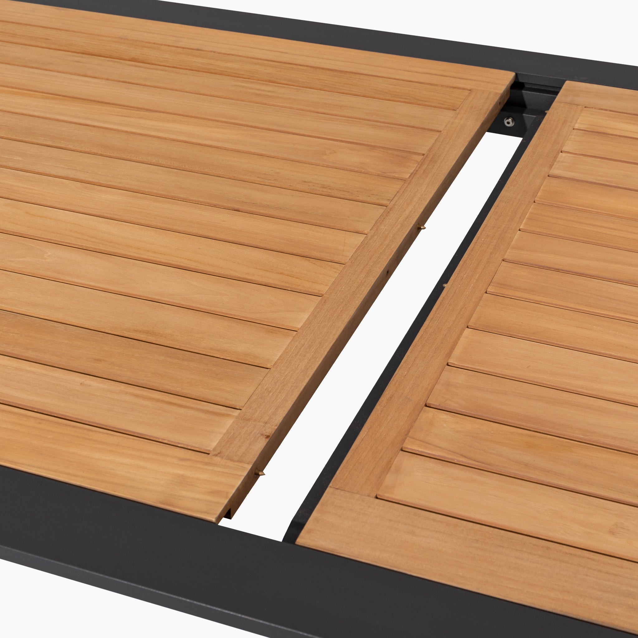 Close-up of the Kalama 8 Seat Rectangular Extending Dining Set’s teak outdoor table with an expandable leaf, showing grooves and a black metal frame in olive green.