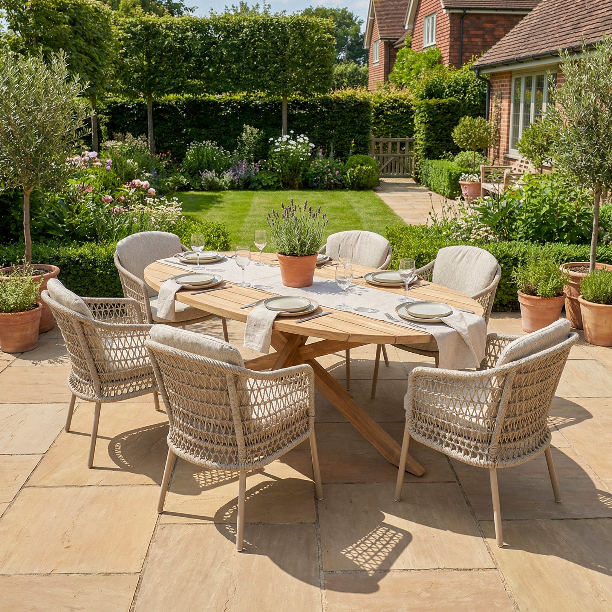 The Puccini 6 Seat Oval Dining Set in Latte is arranged for dining in a sunny, landscaped garden.