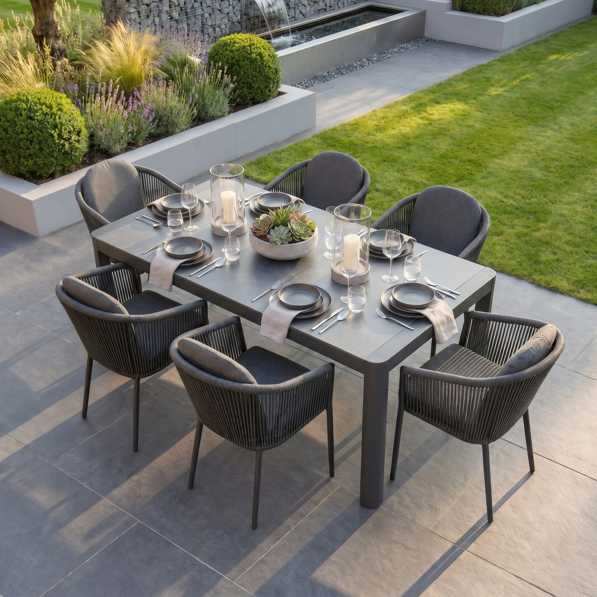 Host stylish gatherings with the Ravona 6 Seat Rope Extending Dining Set (162-222cm) in Charcoal, featuring modern black chairs and a spacious table—perfect for outdoor dining with friends and family.