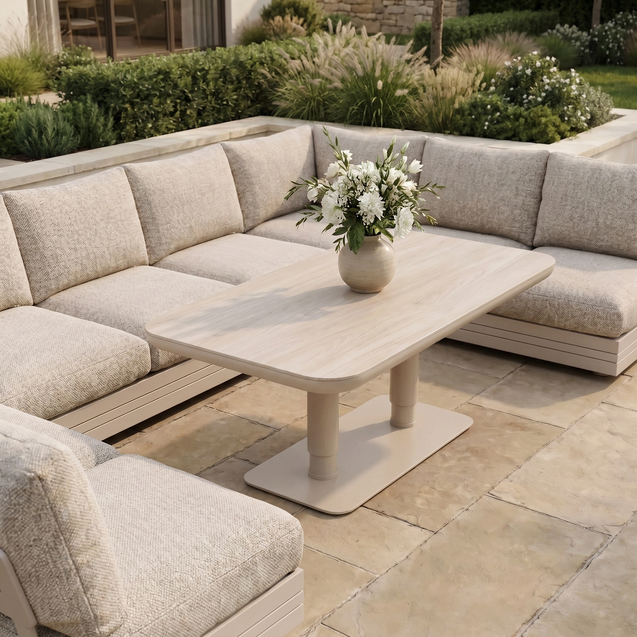The Savona Luxury Outdoor Large U-Shape Corner Sofa Set in Oatmeal features an Altura Rising Table, creating an elegant alfresco setting on a stone patio.