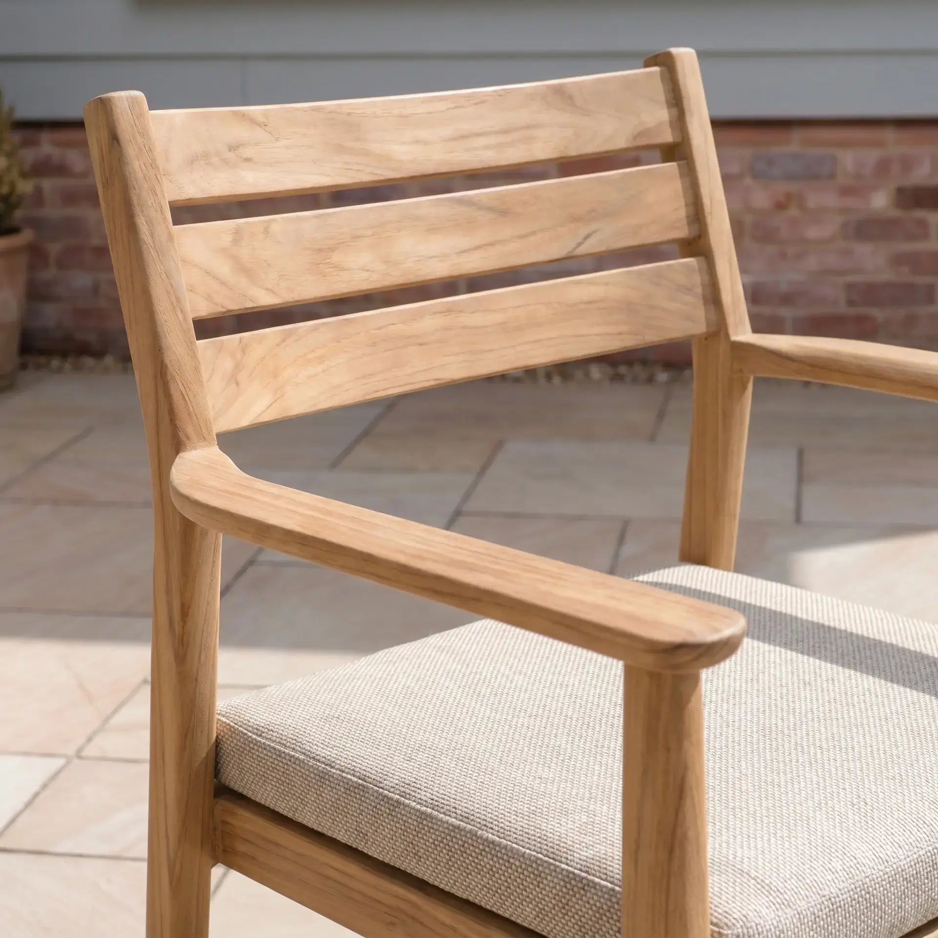The Siena 6 Seat Dining Set in Fawn features light wooden outdoor chairs with slatted backs and cushioned seats, ideal for your stone patio dining experience.